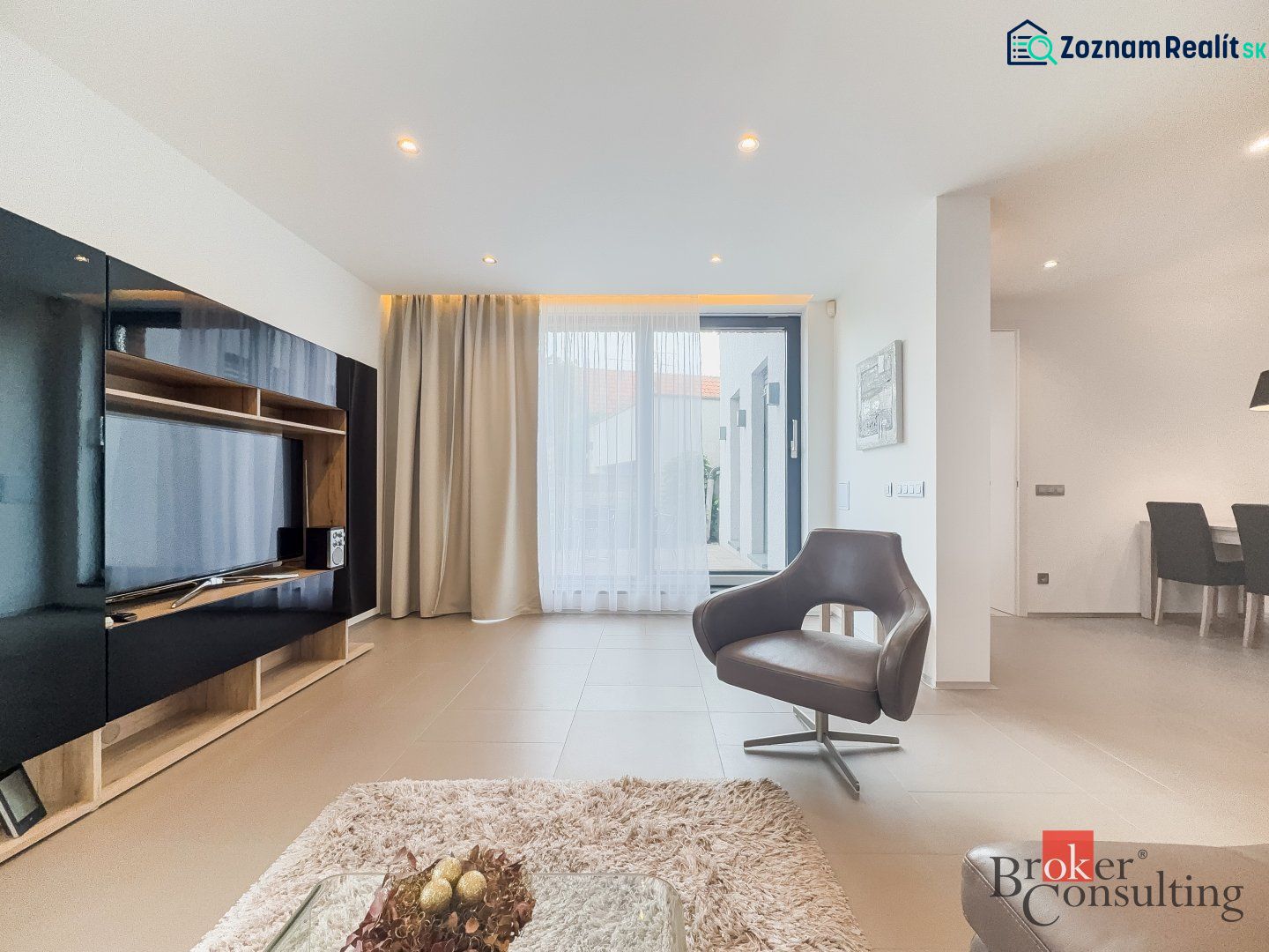 Living area in a 2-room apartment with a television and a comfortable armchair.