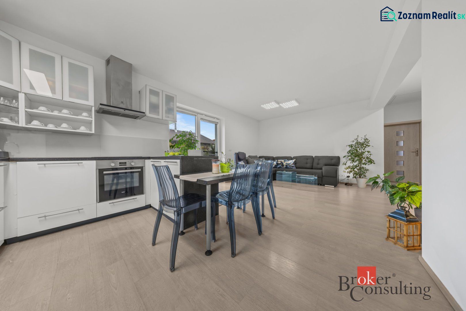 Kitchen and living room in a family house with a wooden decor floor, modern furniture, plants.