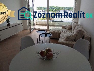 Living room in a two-room apartment with a wooden decor floor and a balcony.