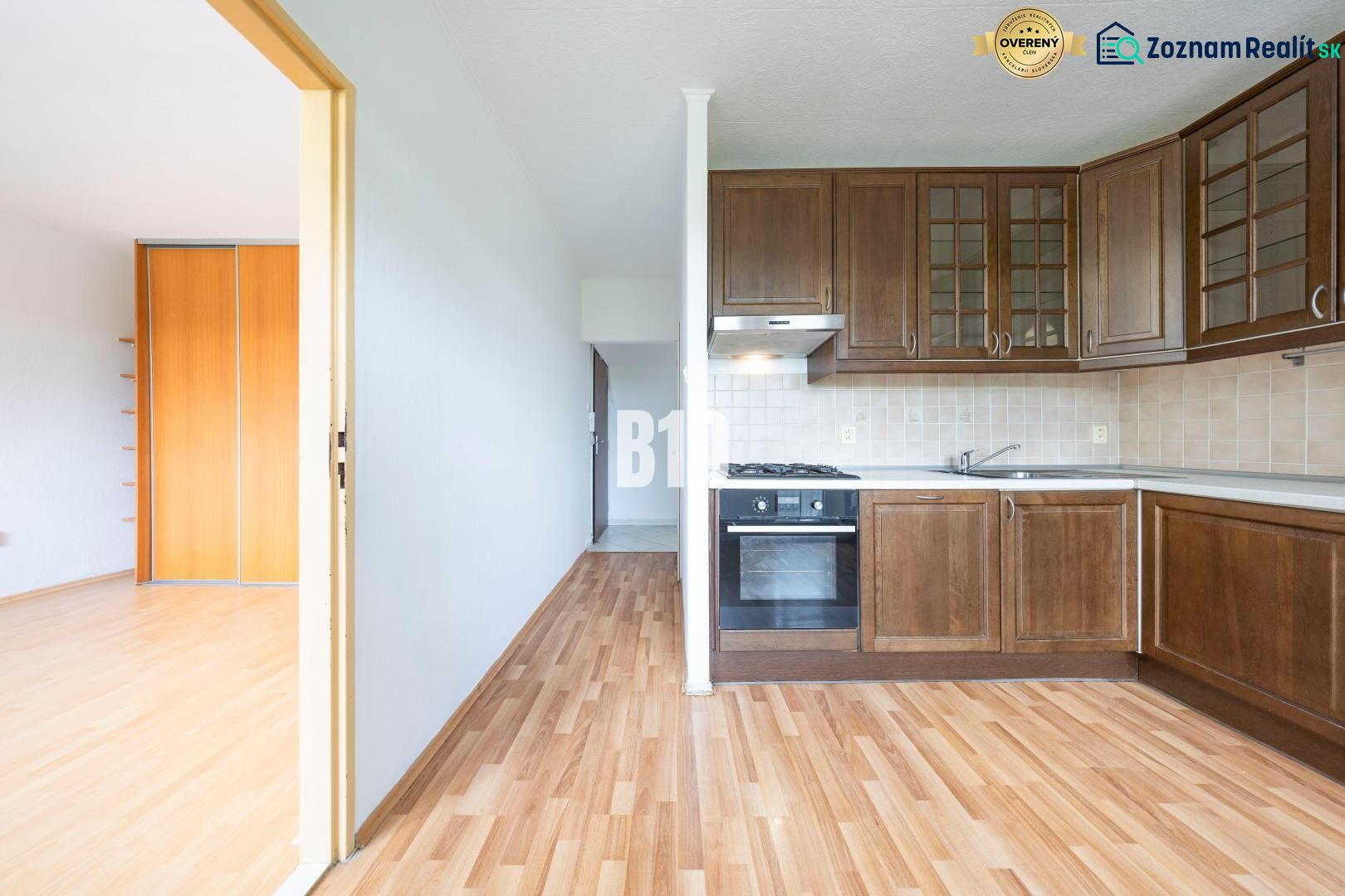 A kitchen with wooden cabinets and a floor with a wooden decor in a 2-room apartment.