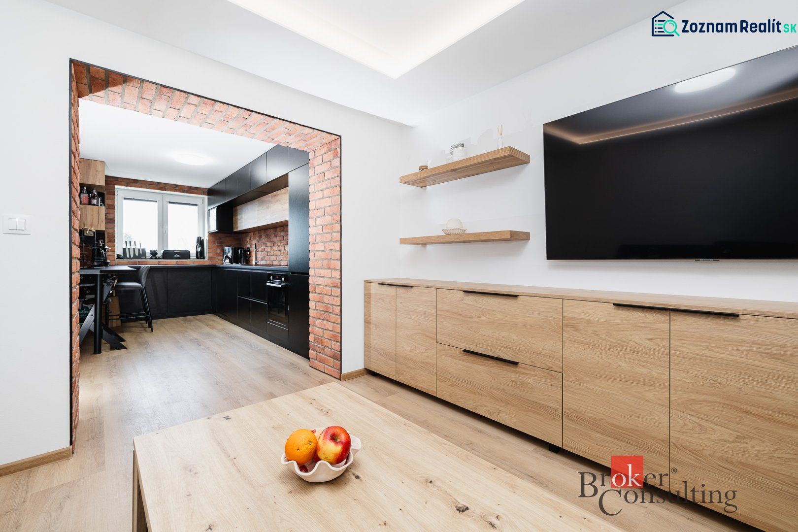 A kitchen in a 2-room apartment with brick details and a wooden decor floor.