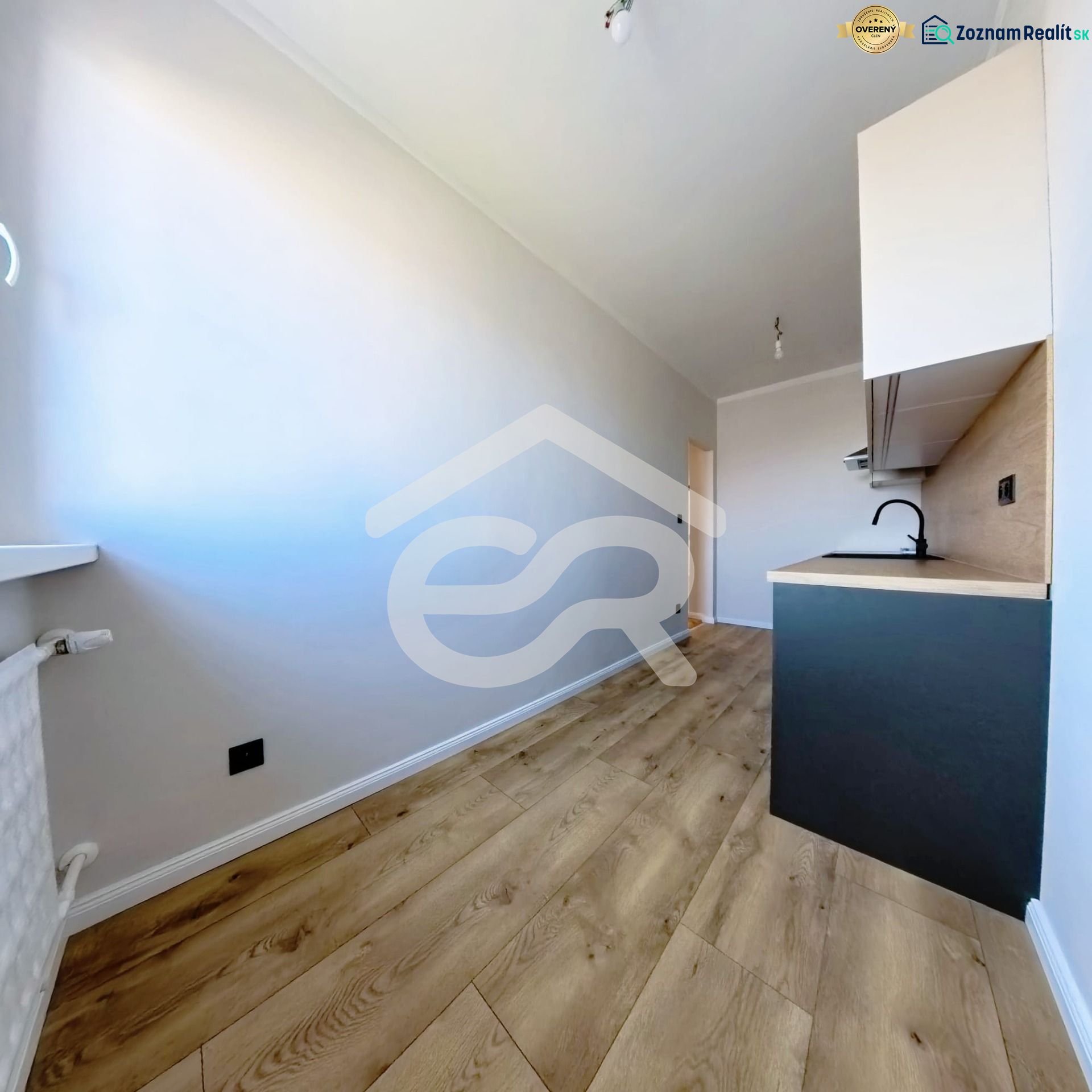 A kitchen in a 3-room apartment with a wooden decor floor and light walls.