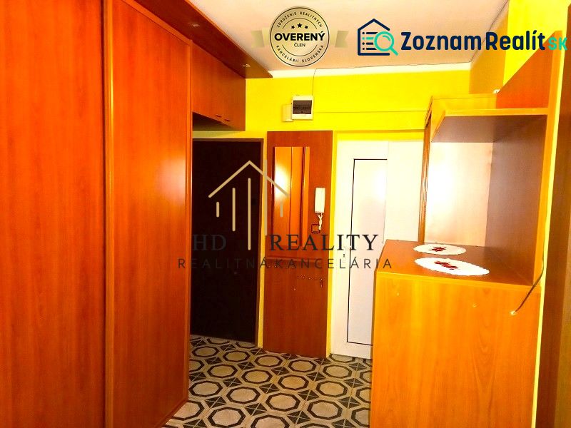 A hallway in a 4-room apartment with wooden furniture and patterned flooring.