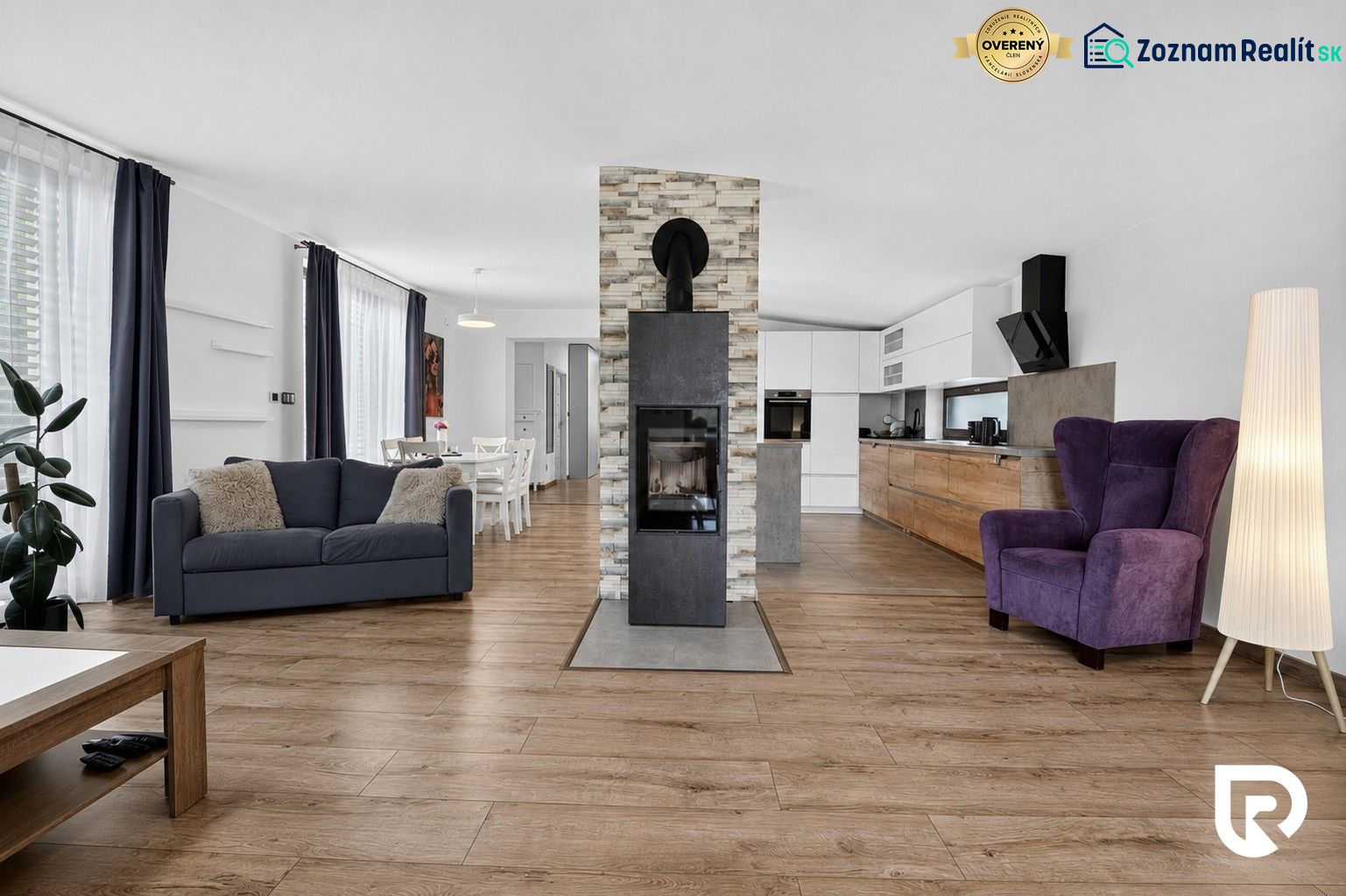 Living room with a sofa, fireplace, and wooden decor flooring in a family house.