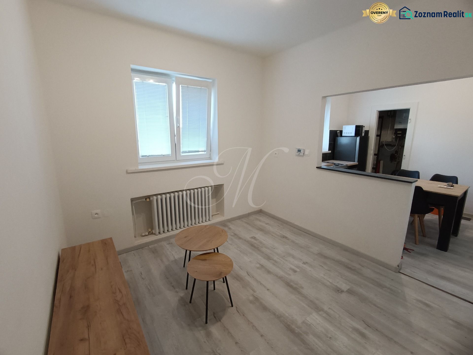 Living room in a two-room apartment with a wooden decor floor and simple furniture.