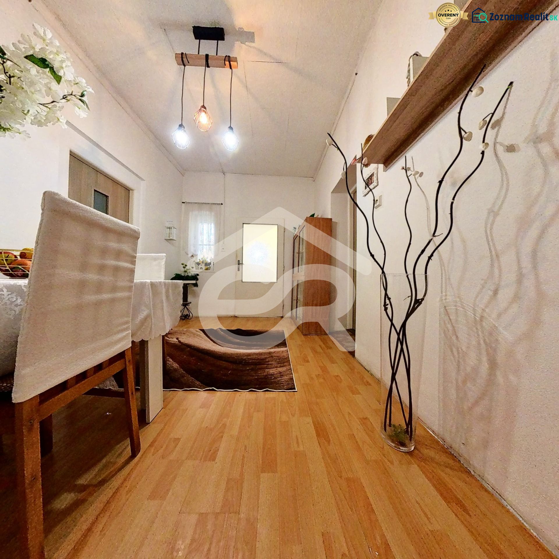 Interior of a family house with a dining table, wood-patterned flooring, and pendant lamps.