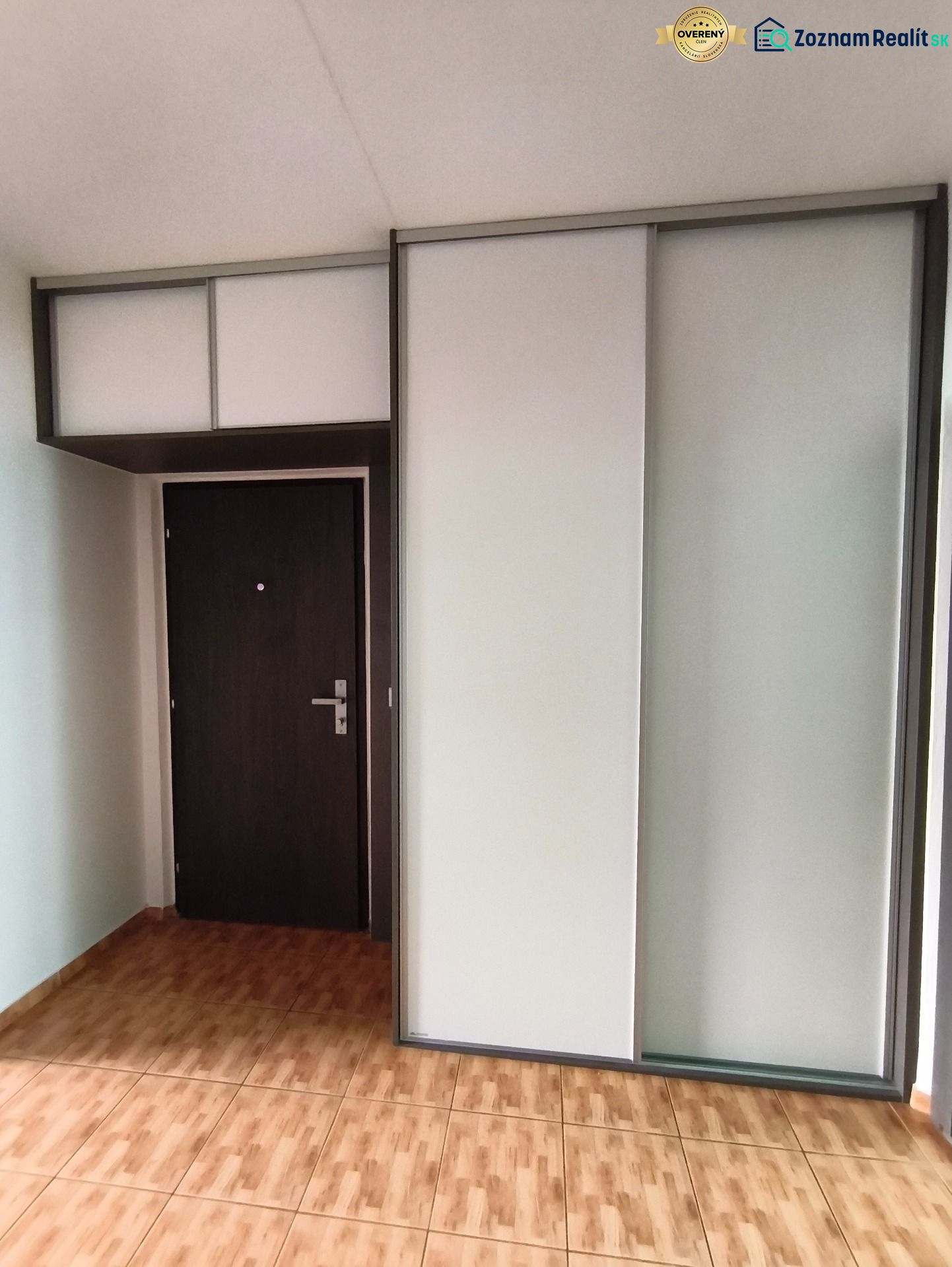 Entrance hall in a 3-room apartment with wood-patterned flooring and a built-in wardrobe.