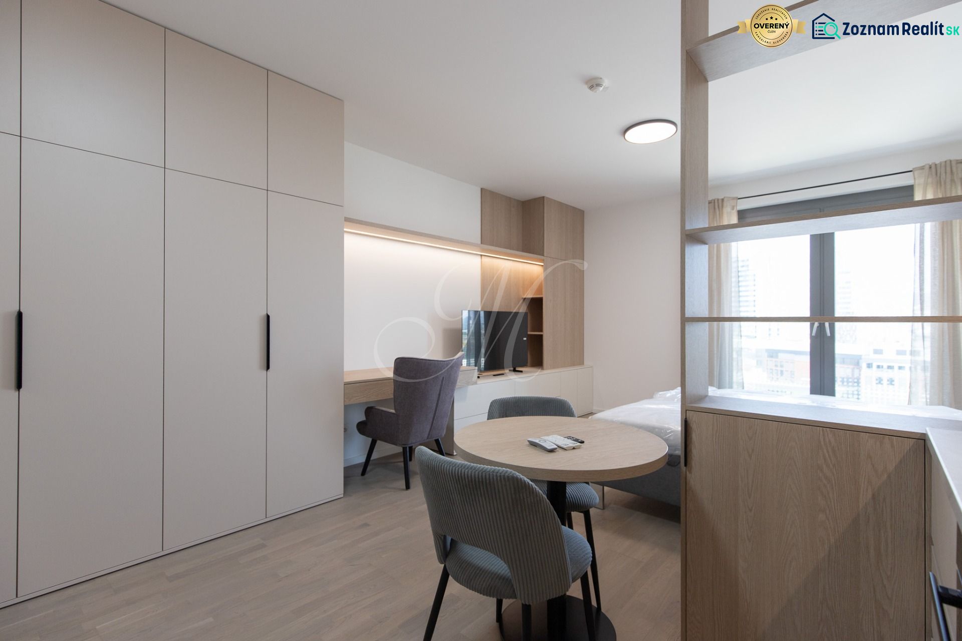 1-room apartment with wood-patterned flooring, wardrobes, a table, chairs, and a window.