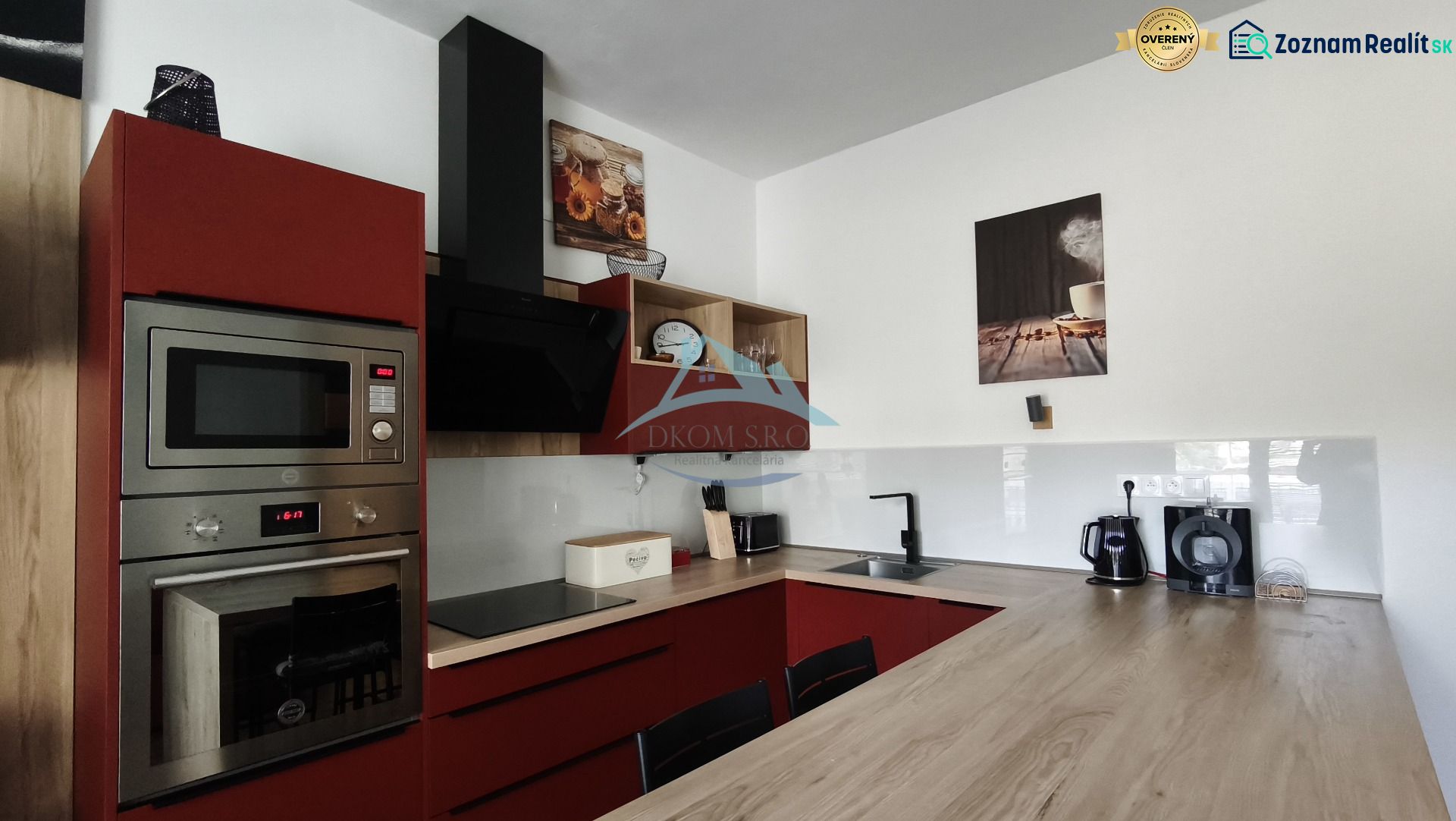 A kitchen with red cabinets and appliances in a 2-room apartment with a wood-patterned floor.