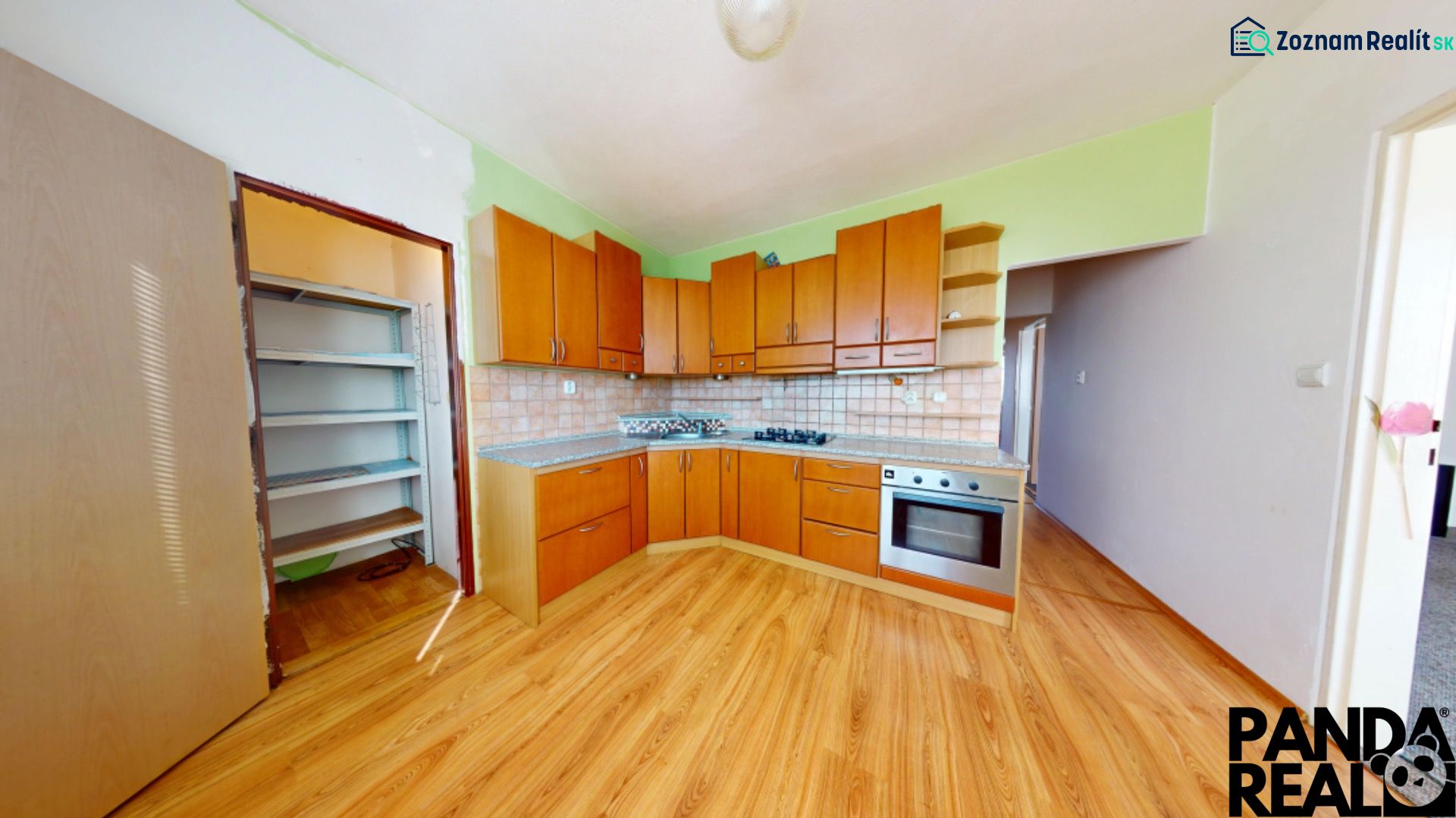 A kitchen in a 3-room apartment with a wooden decor floor and built-in appliances.