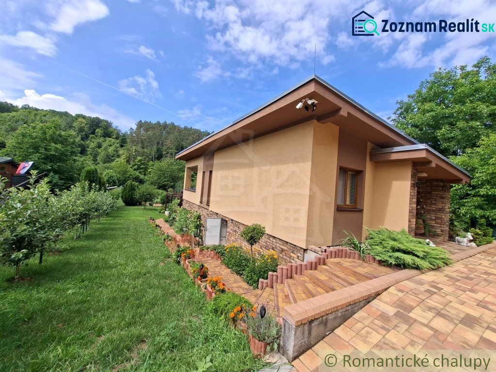 A family house in Veľké Uherce surrounded by a green garden and trees.