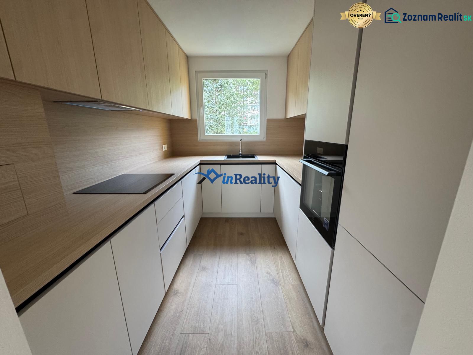 A kitchen with white cabinets and a wood-patterned floor in a 3-room apartment.