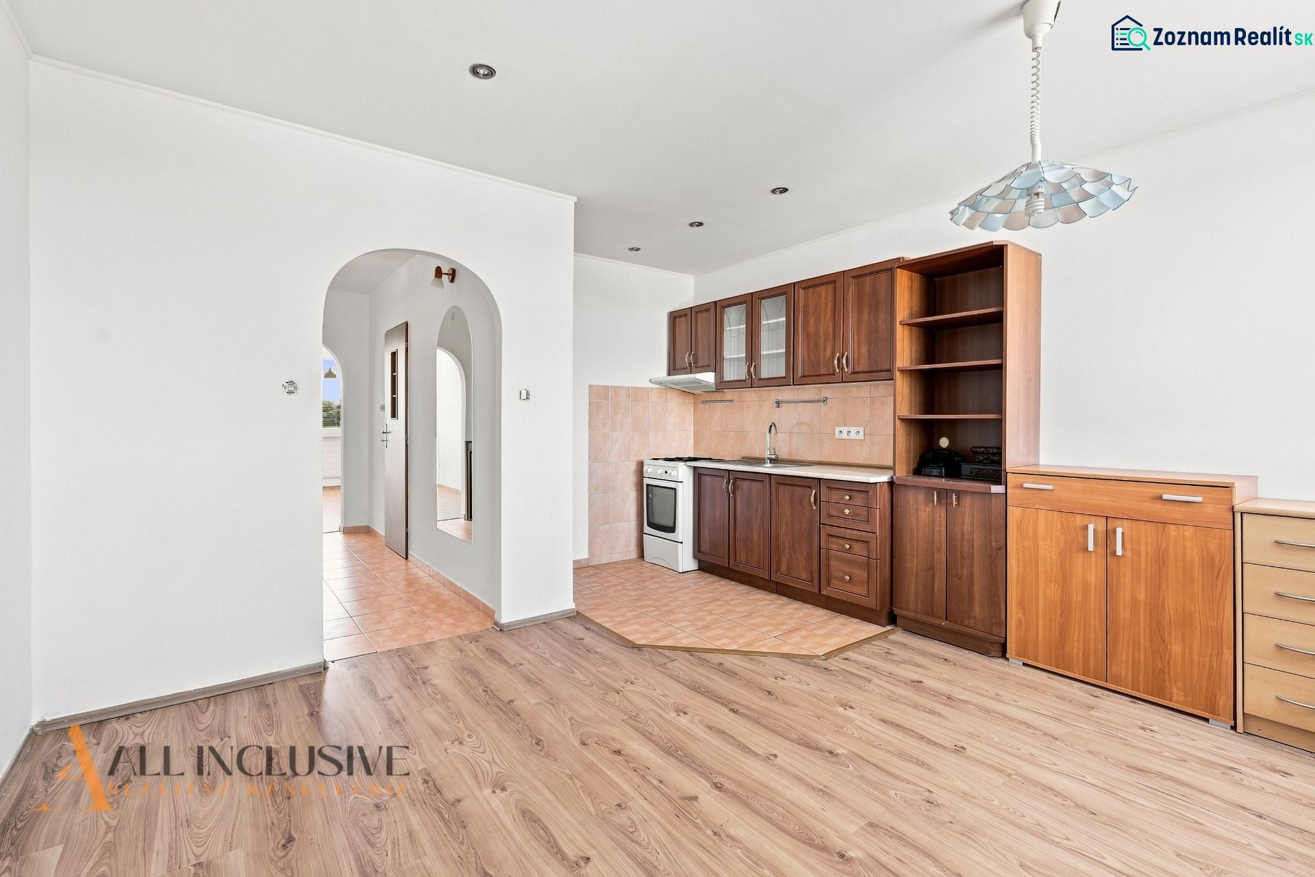 A kitchen in a 2-room apartment with a wooden decor floor and built-in cabinets.
