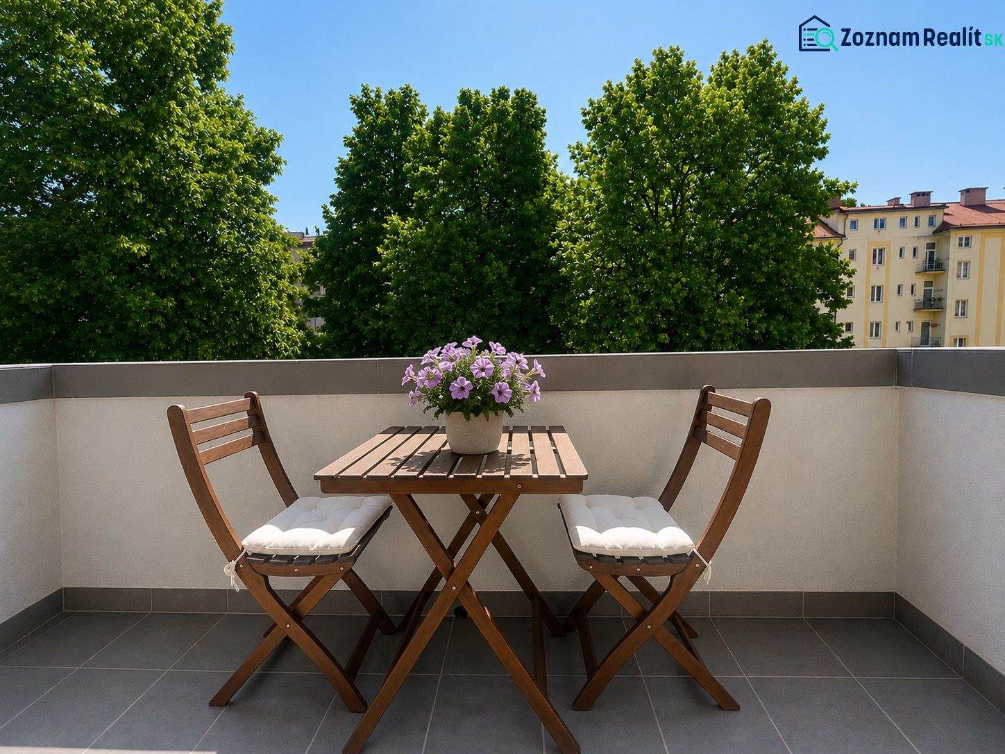Wooden table and chairs with flowers on the terrace of a 2-room apartment in Banská Bystrica.