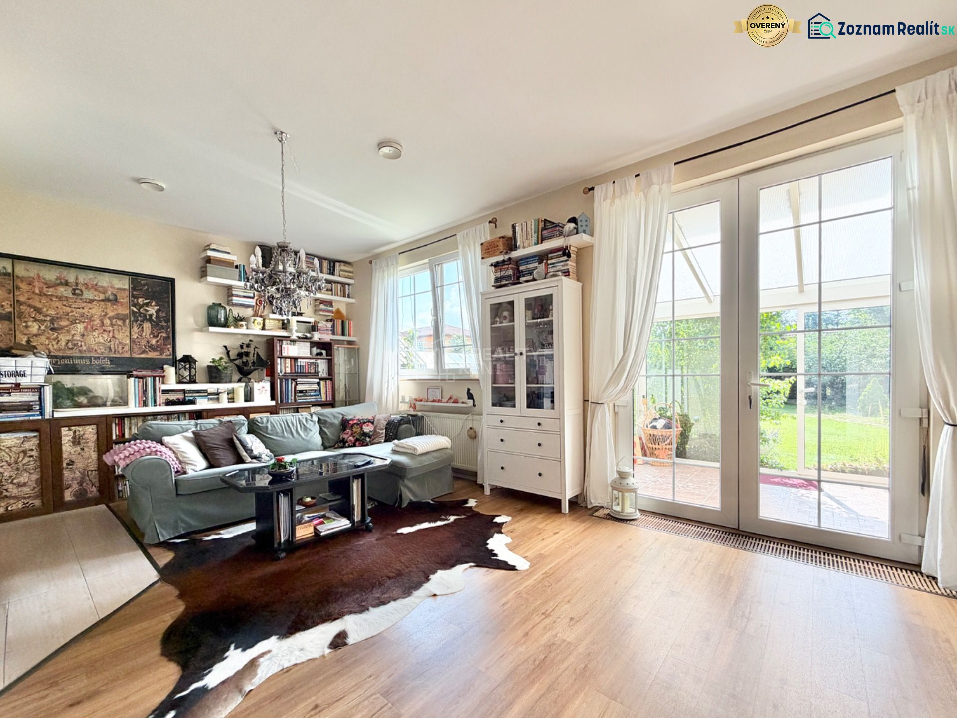 A living room in a family house with a wooden decor floor and a view of the garden.