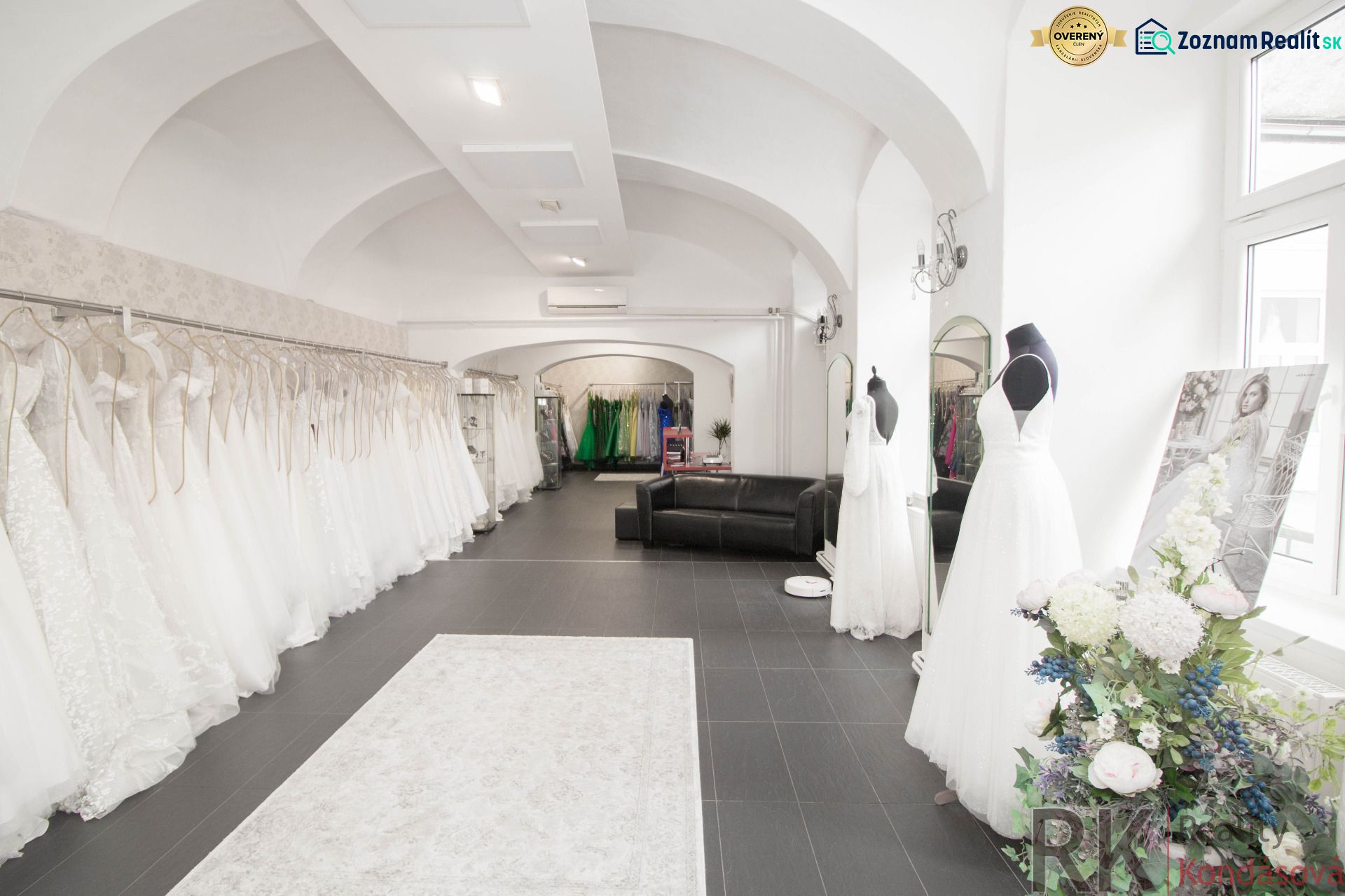 Wedding dress and black couch in a commercial space with arched ceilings.