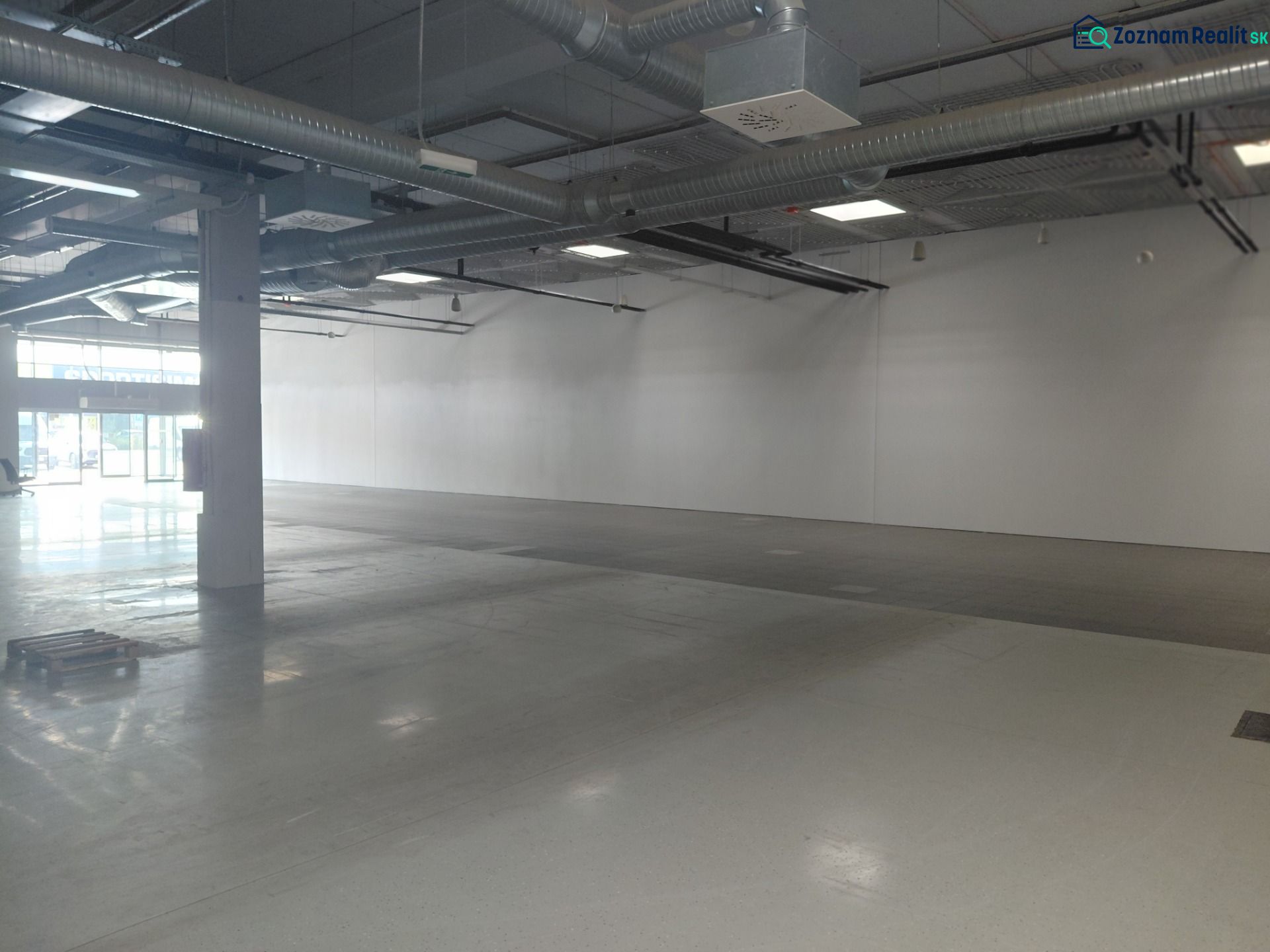 Spacious commercial spaces with concrete flooring and exposed pipes on the ceiling.