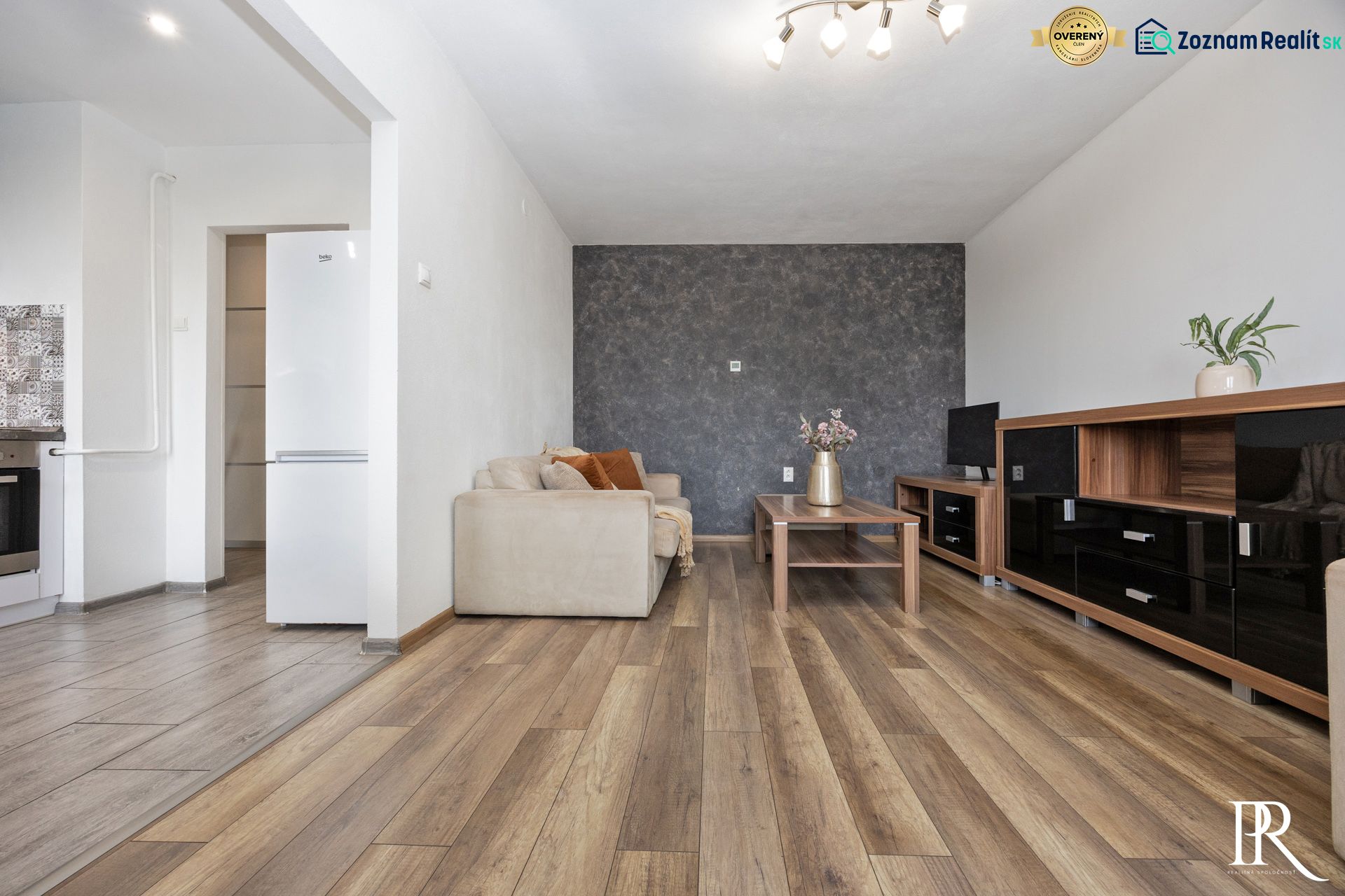Living room in a two-room apartment with a wooden decor floor and a comfortable sofa.