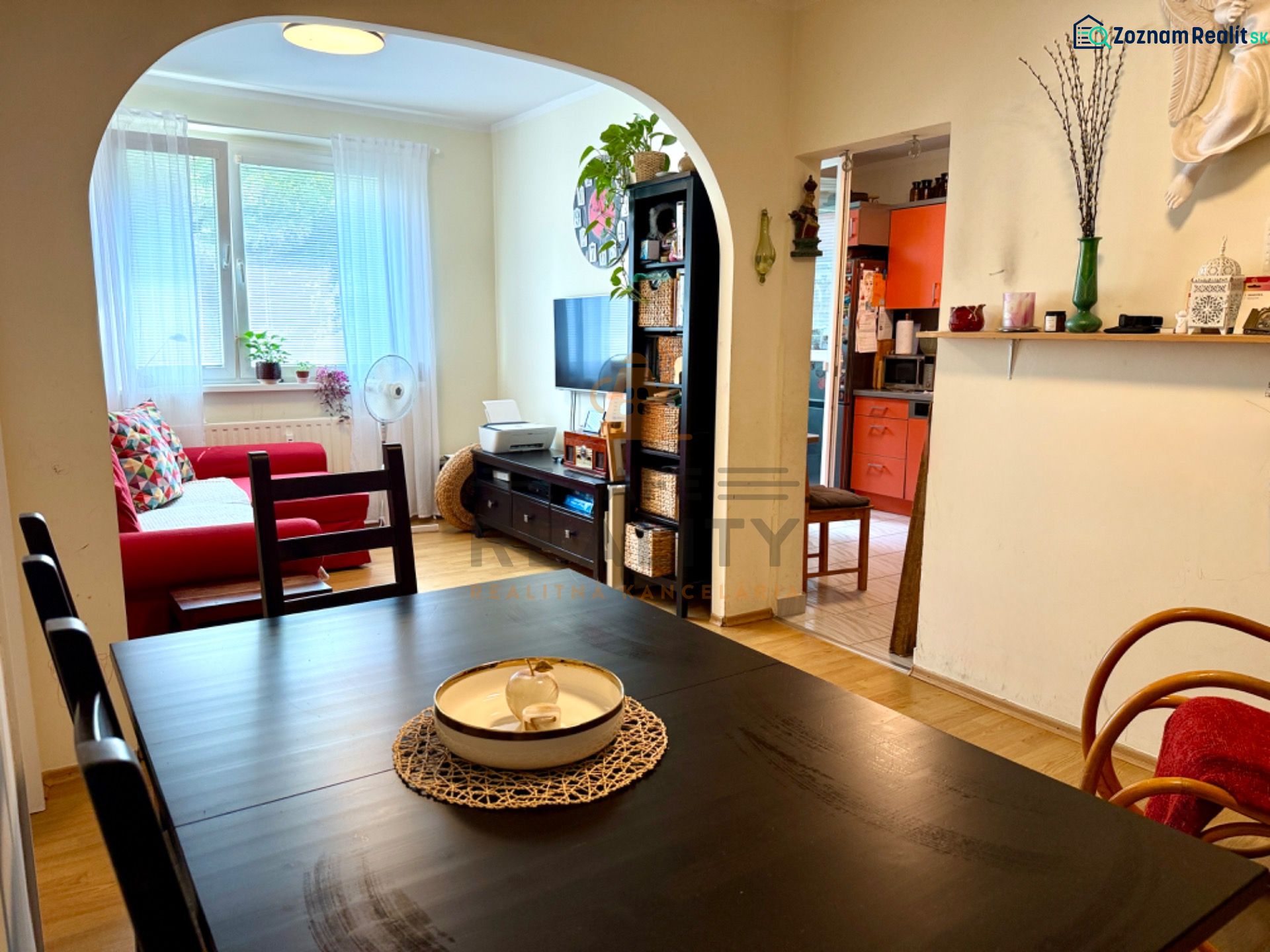 Interior of a 3-room apartment with a living room, kitchen, wooden decor flooring, and a dining table.