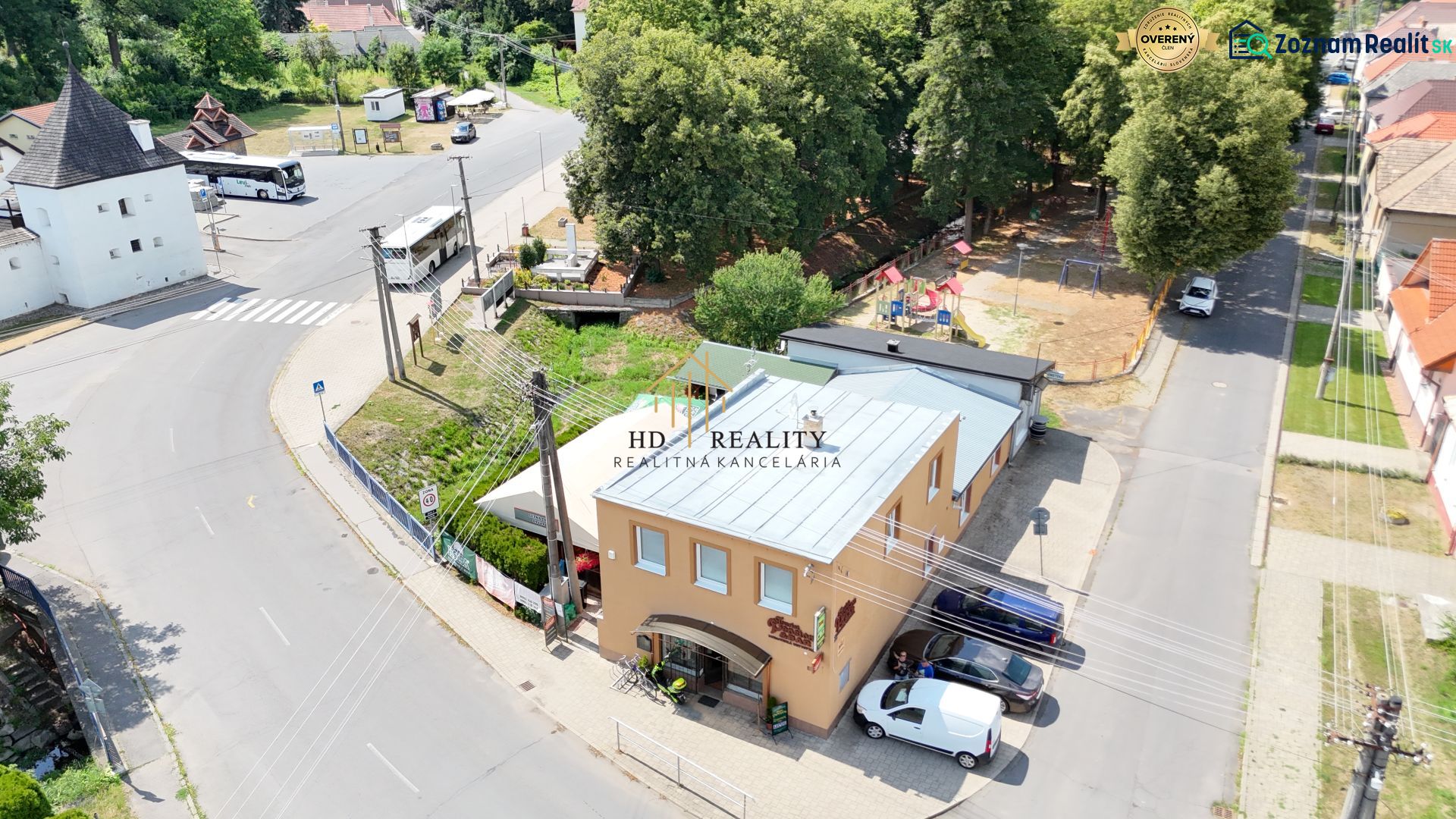 Commercial premises in Divín with a bus stop and surrounding greenery.