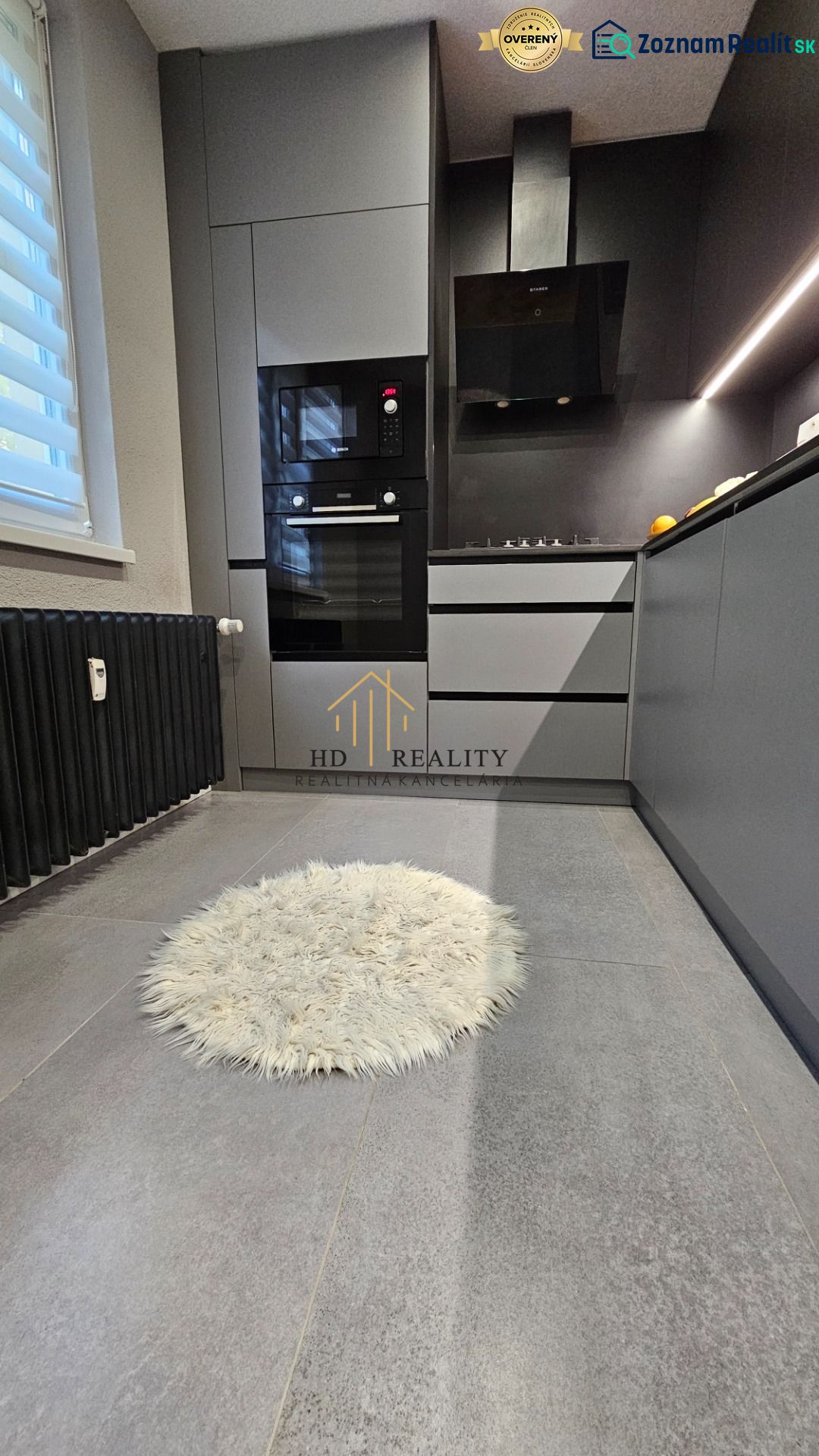 A stylish kitchen in a 2-room apartment with modern appliances and a round rug.