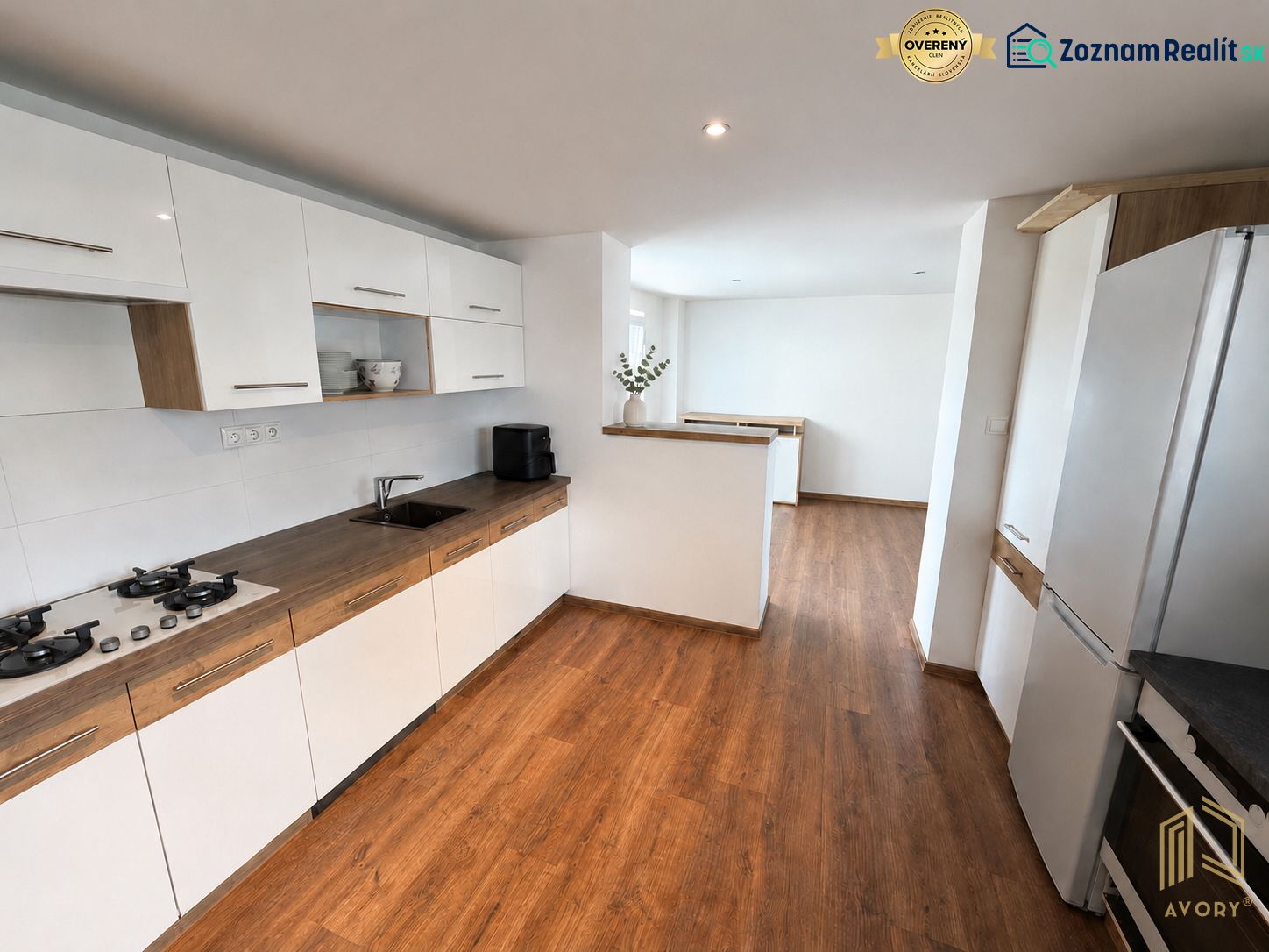 A kitchen in a family house with white cabinets and a wood-patterned floor.