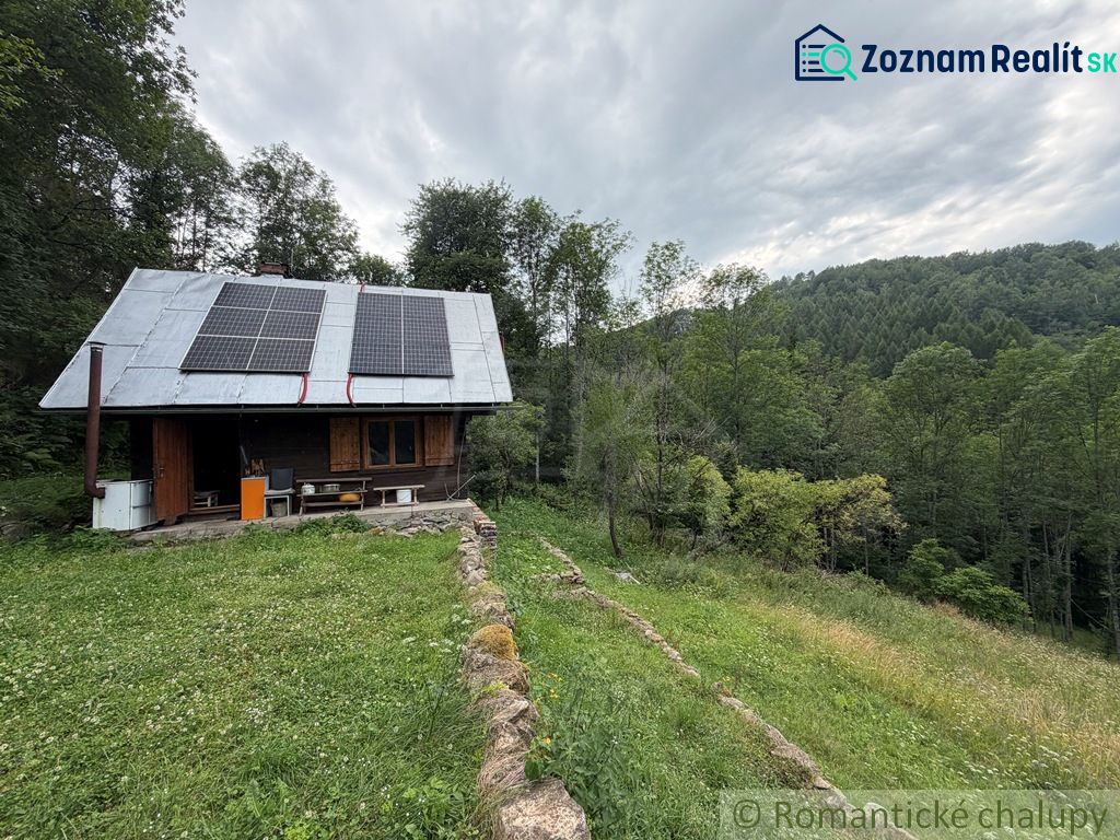 A family house in Kokava nad Rimavicou, with a lawn, solar panels, and surrounded by forest.