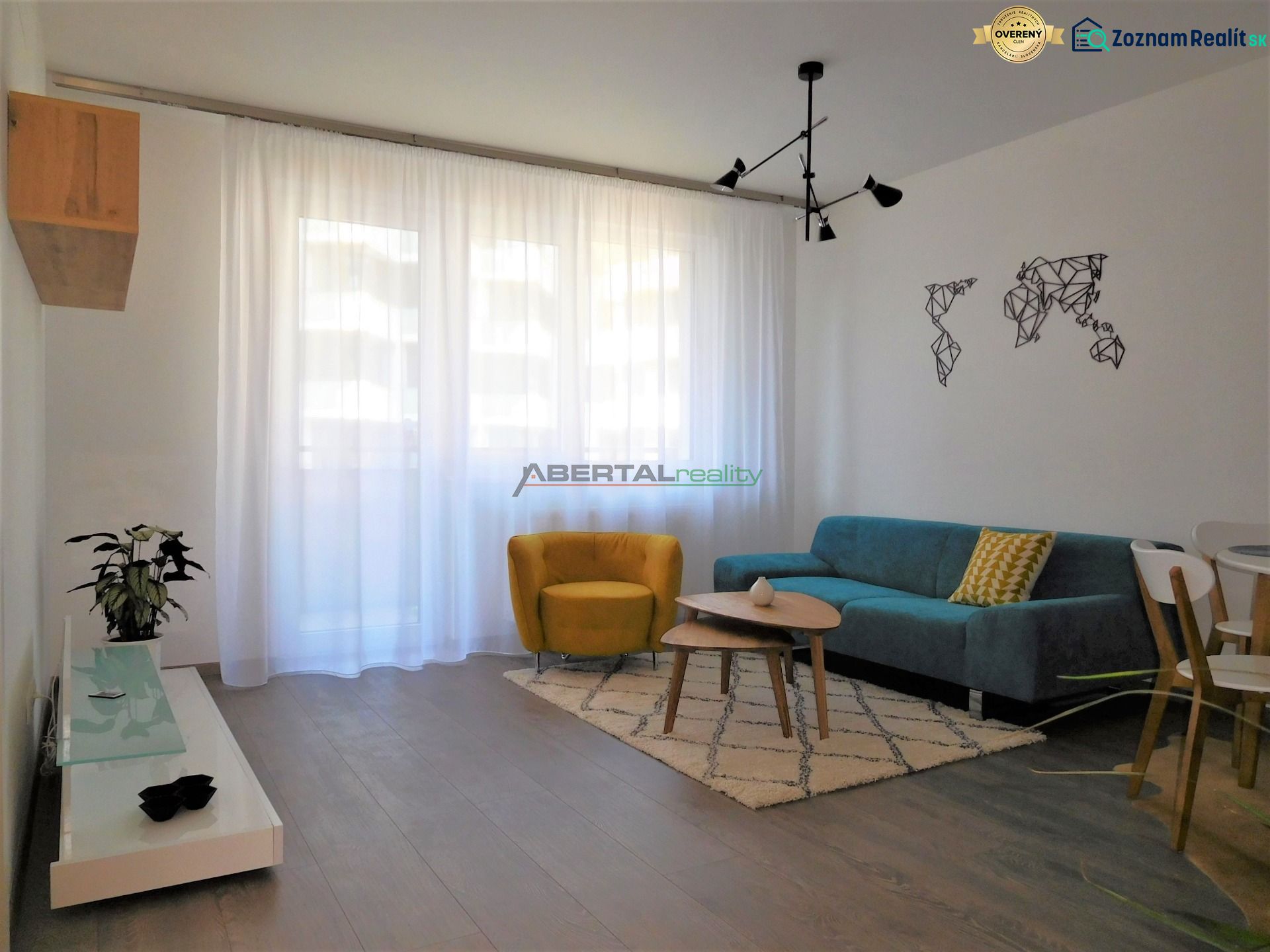Living room in a two-room apartment with a wooden decor floor, a blue couch, and a yellow armchair.