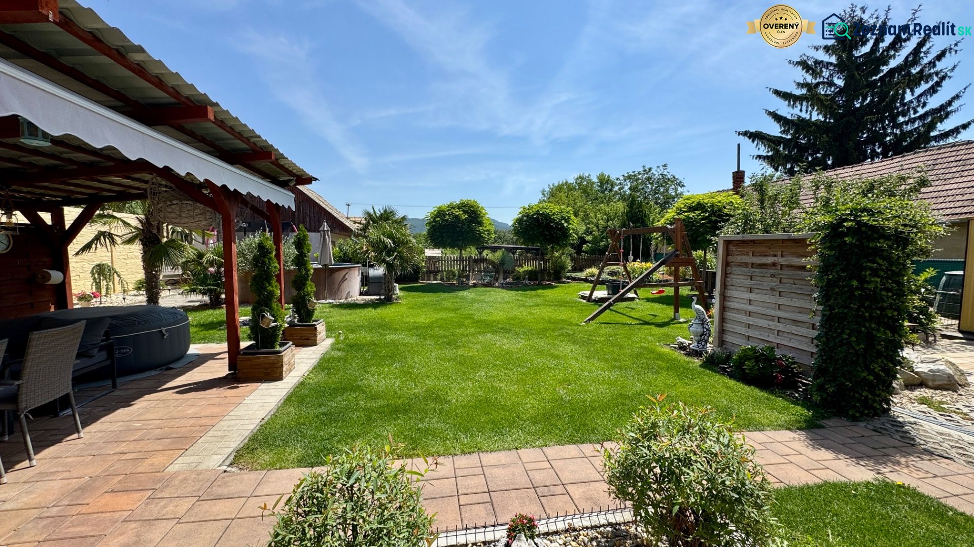 The garden of a family house in Čakajovce with a gazebo, lawn, and children's playground.