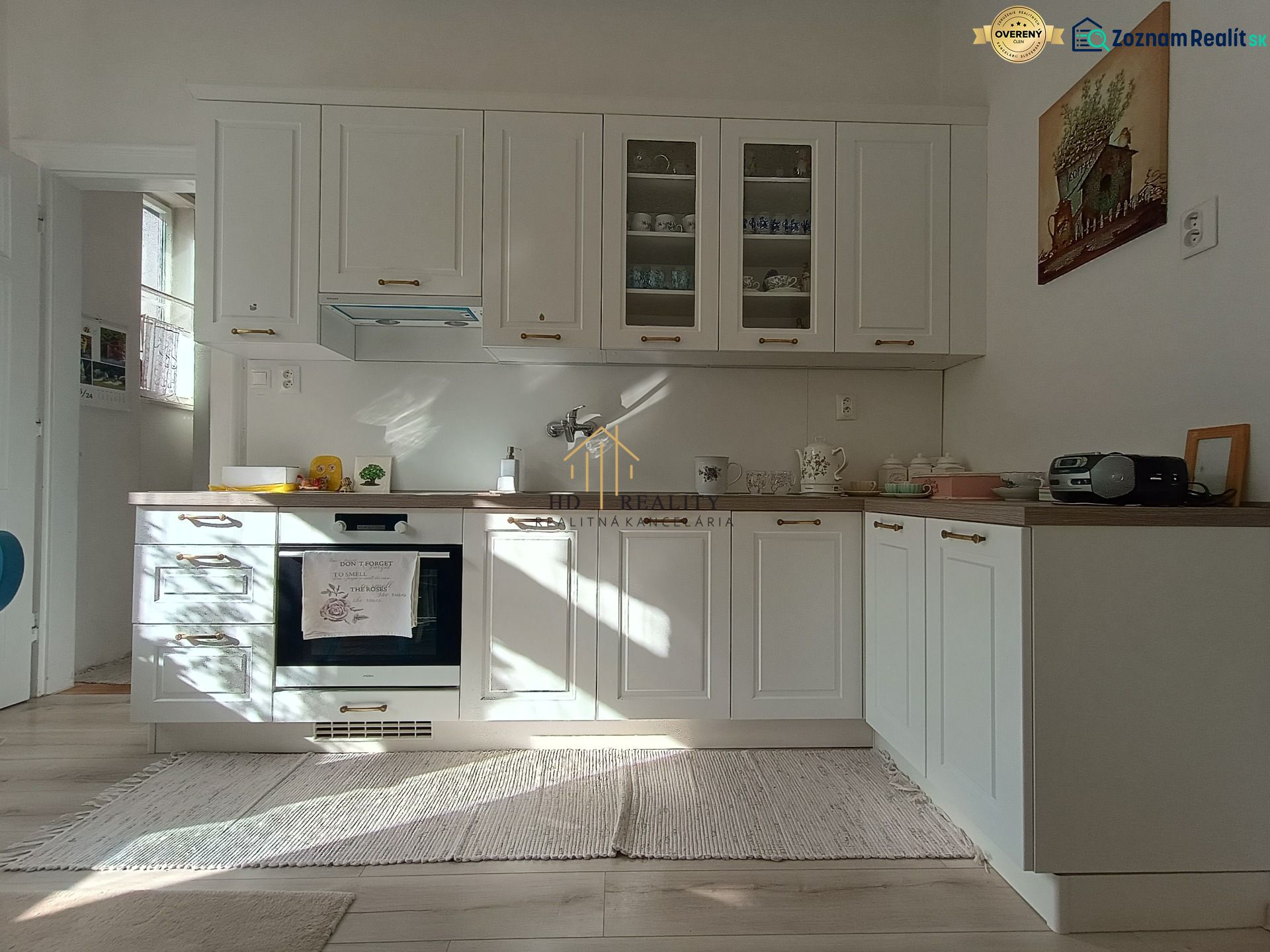 A kitchen with white cabinets, wood-patterned flooring, and light in a 4-room apartment.