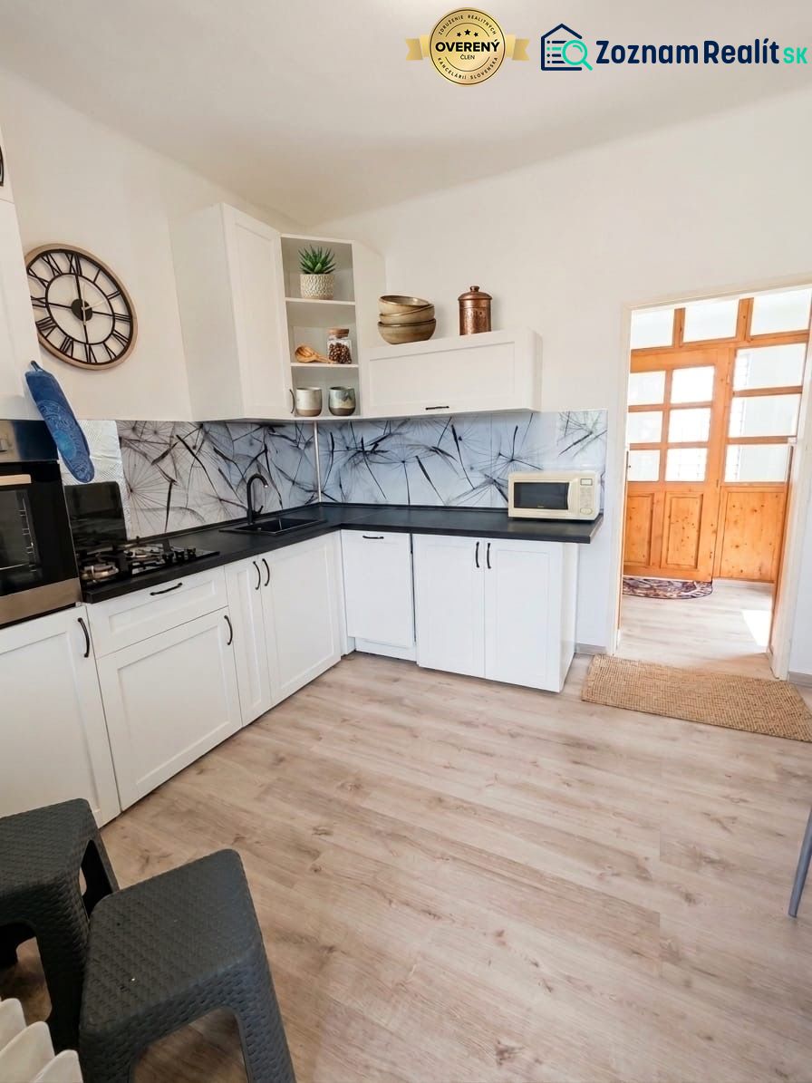 A kitchen in a family house with white cabinets and a wood-patterned floor.