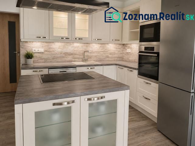 A kitchen in a 2-room apartment with a wood-patterned floor and stainless steel appliances.