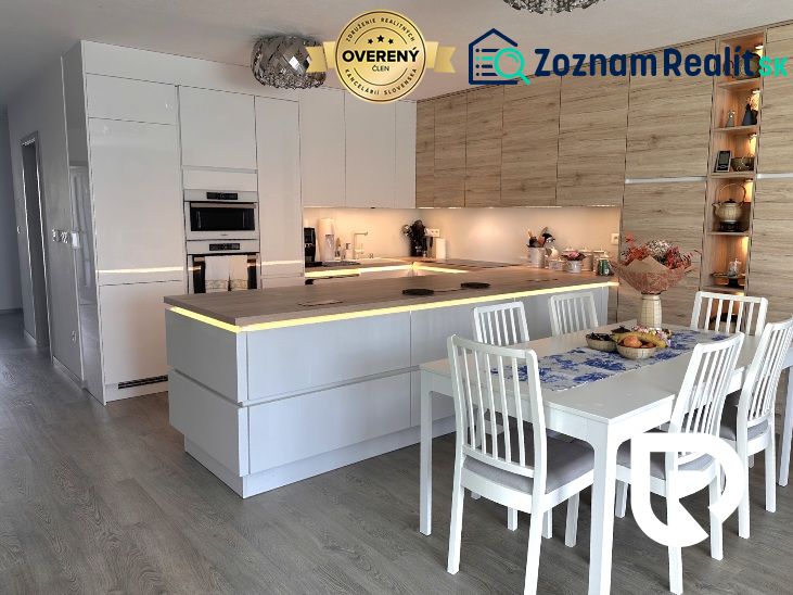 A kitchen in a family house with white cabinets and a wood-patterned floor.