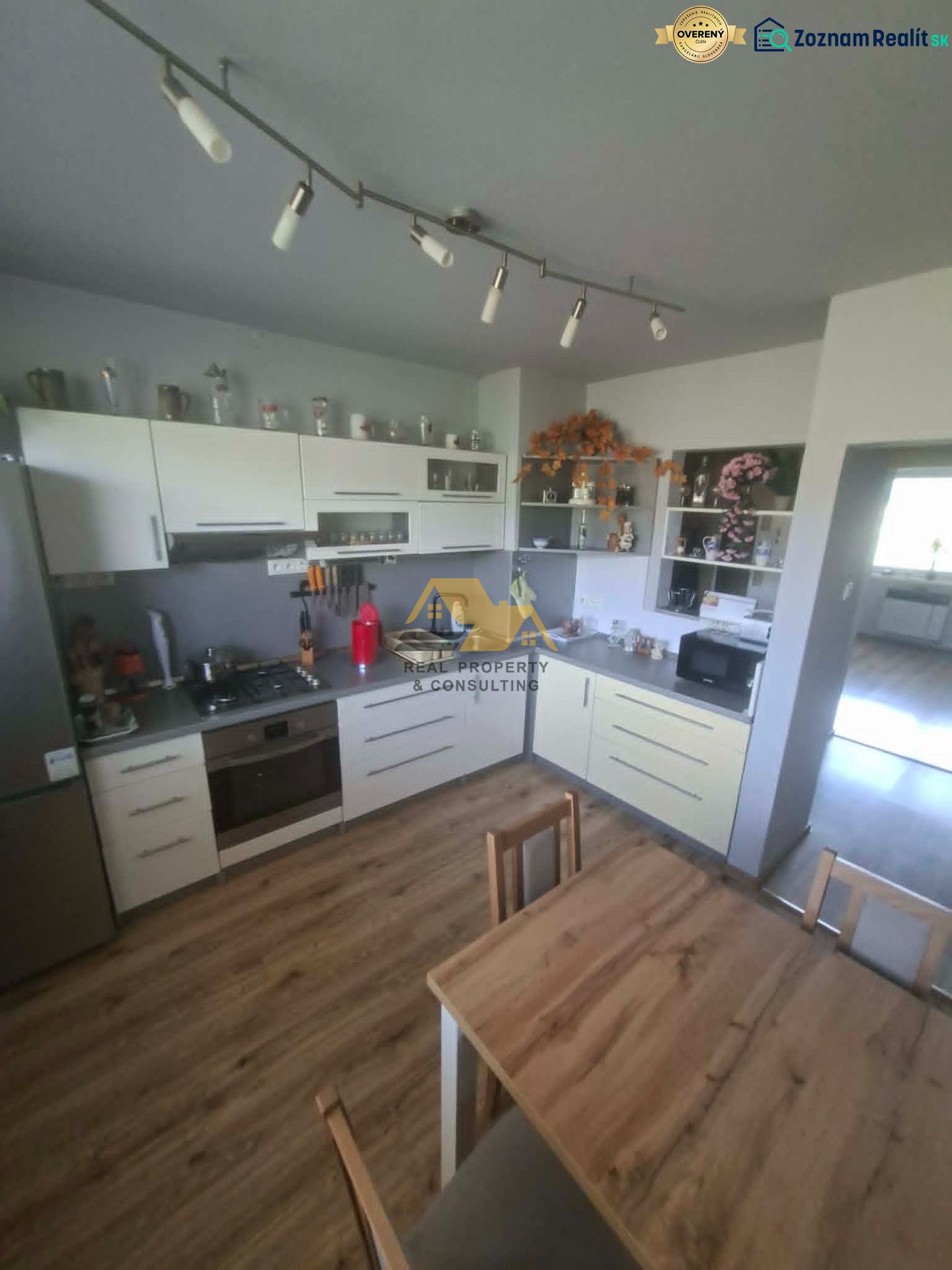 A kitchen with white cabinets and a wood-patterned floor in a 3-room apartment.