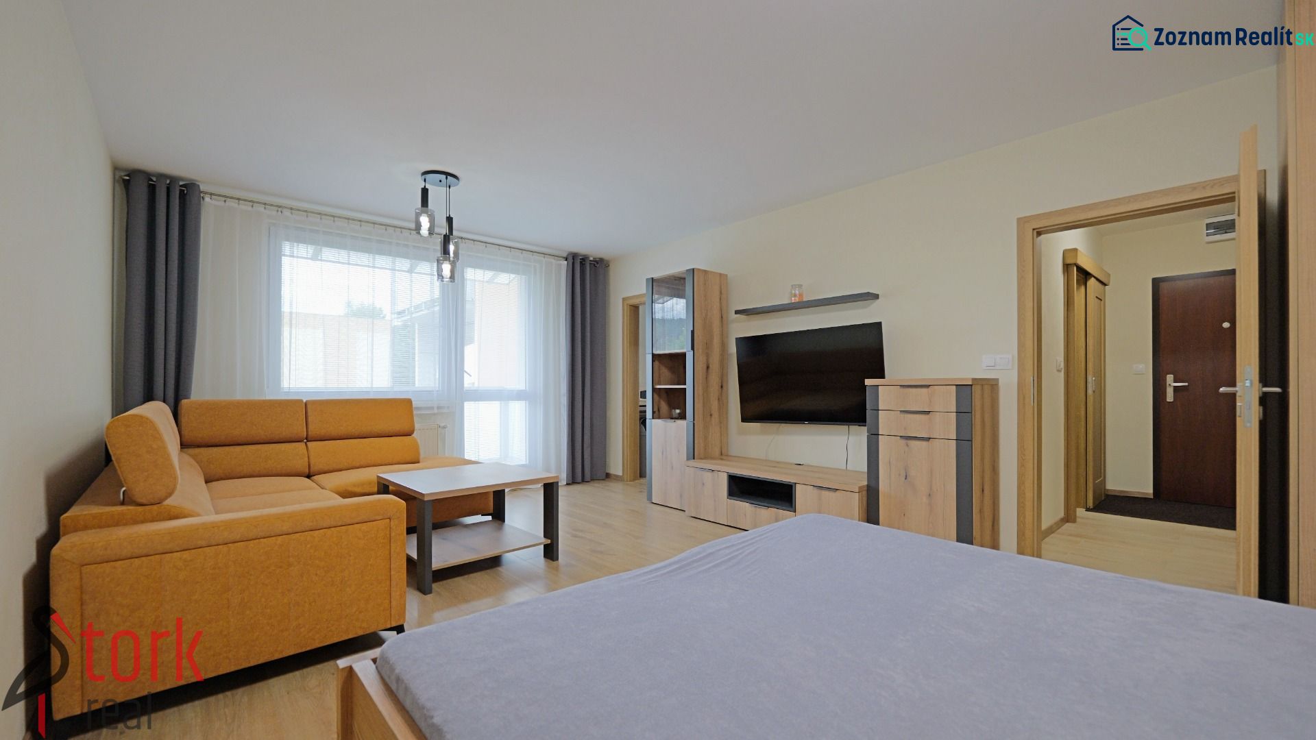 Living room in a studio apartment with a wood-patterned floor and an orange sofa.