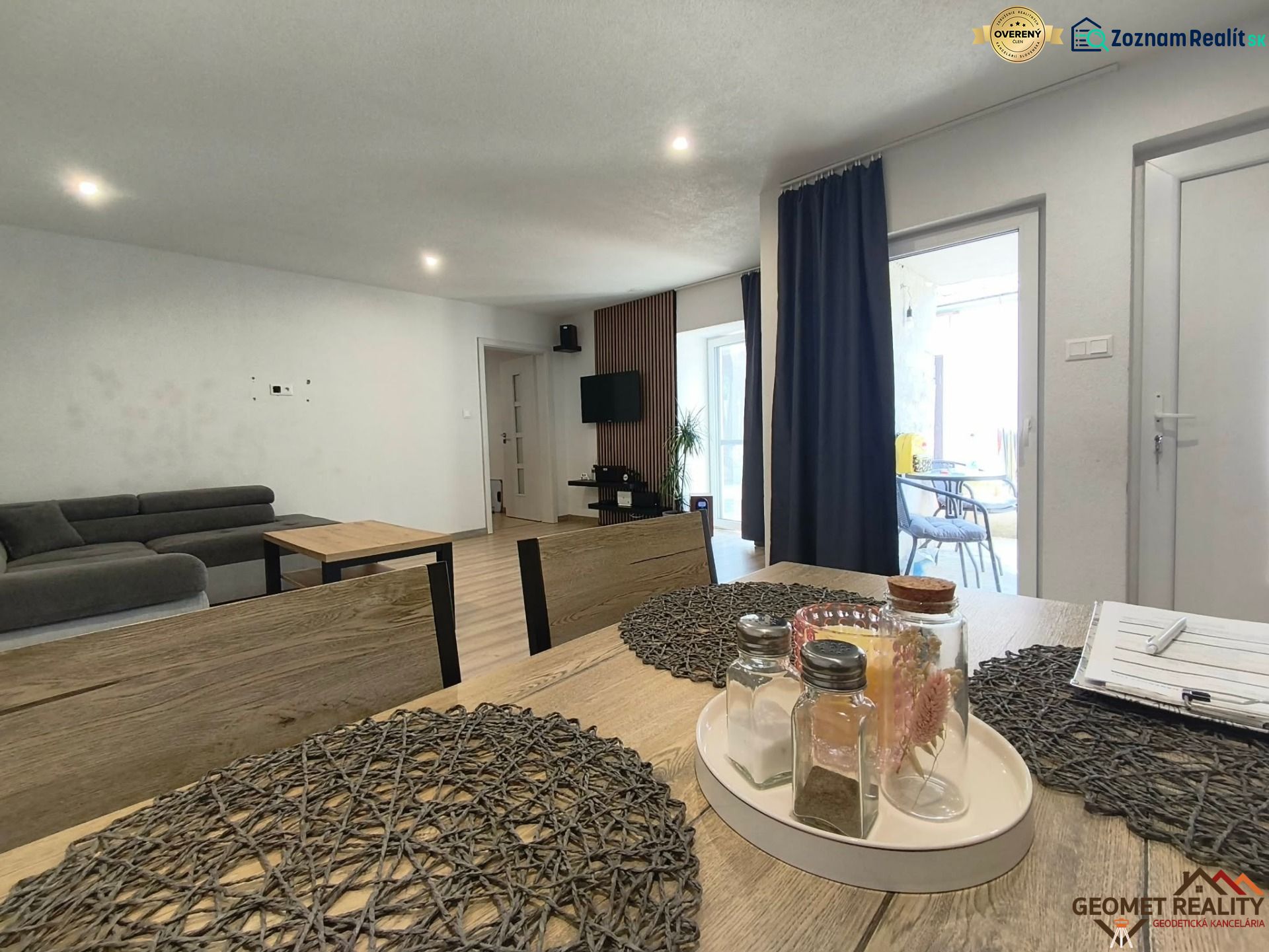 Dining table with decorations, sofa, television, and wooden decor flooring in a family house.