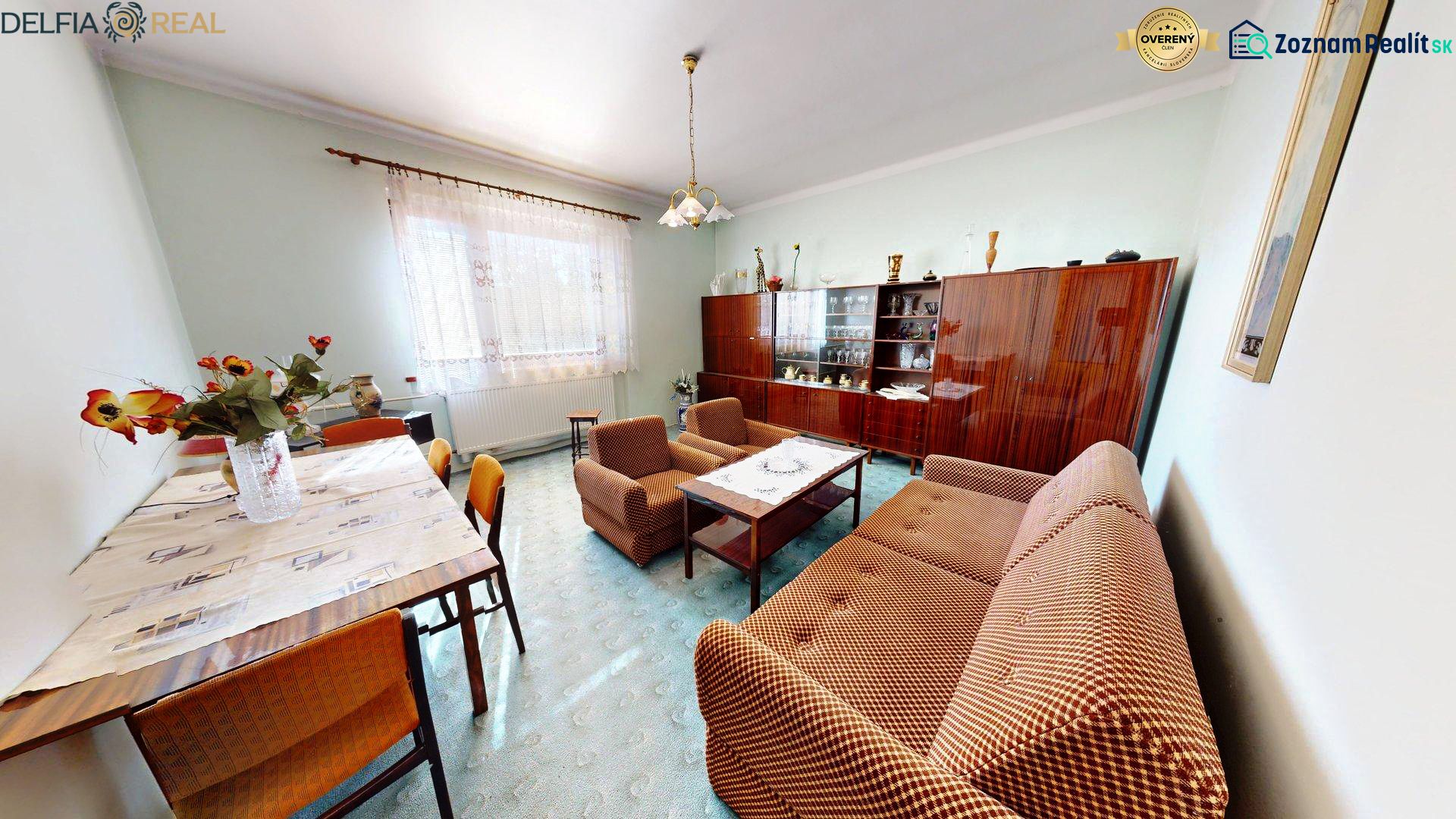 Living room in a family house with a sofa, display cabinet, and dining table.