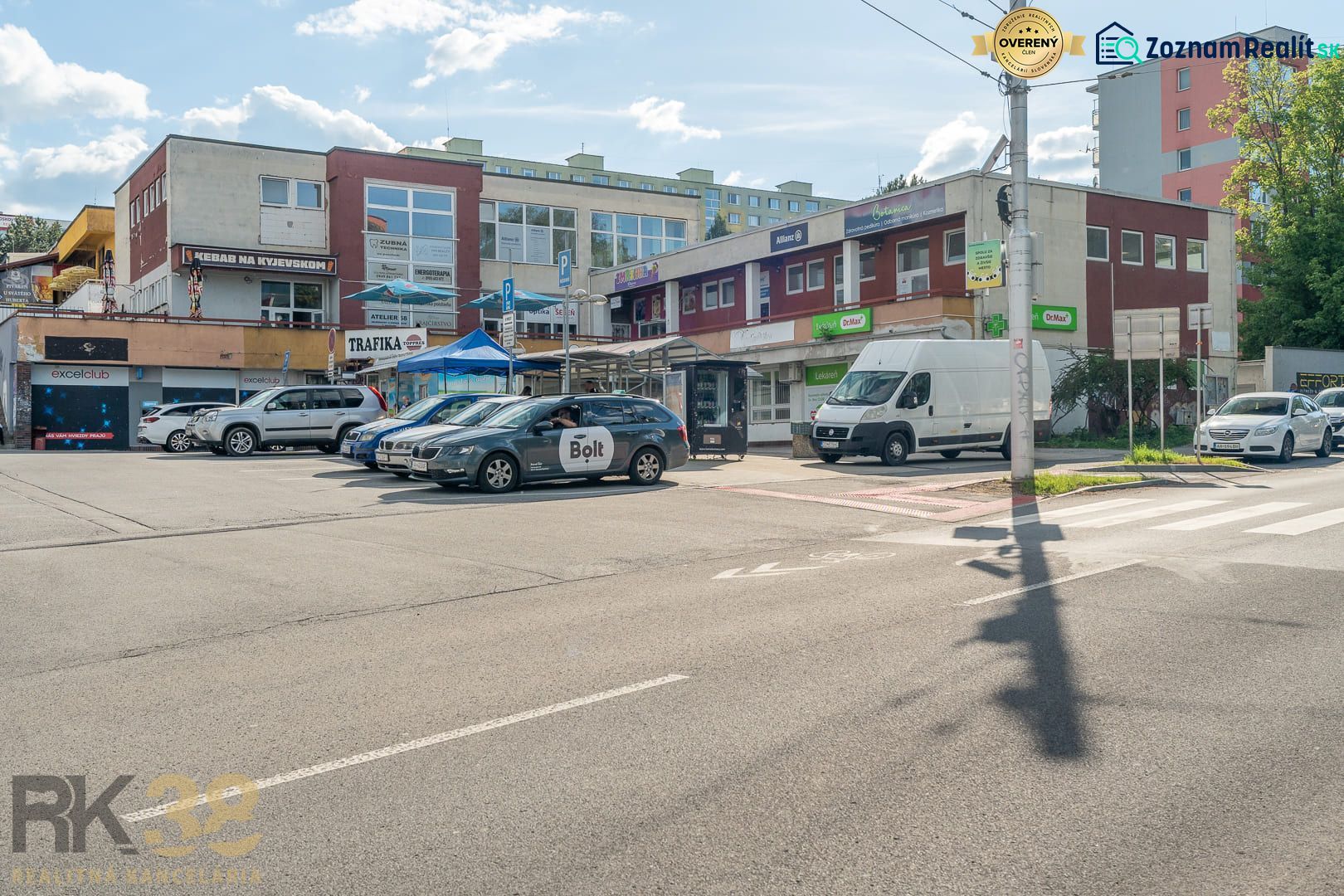 A street with a building in Banská Bystrica, cars, and advertising signs on businesses.