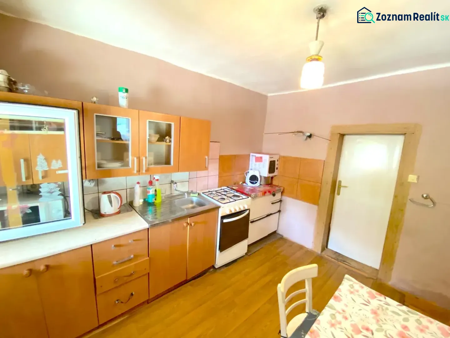 A kitchen in a family house with a wooden decor floor and wooden cabinets.