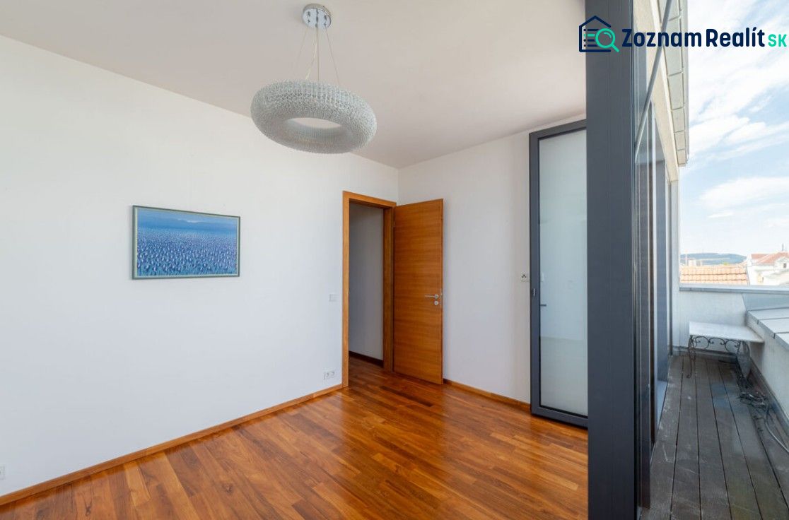 A room in a 2-room apartment with a wooden decor floor, a painting, and glass doors.