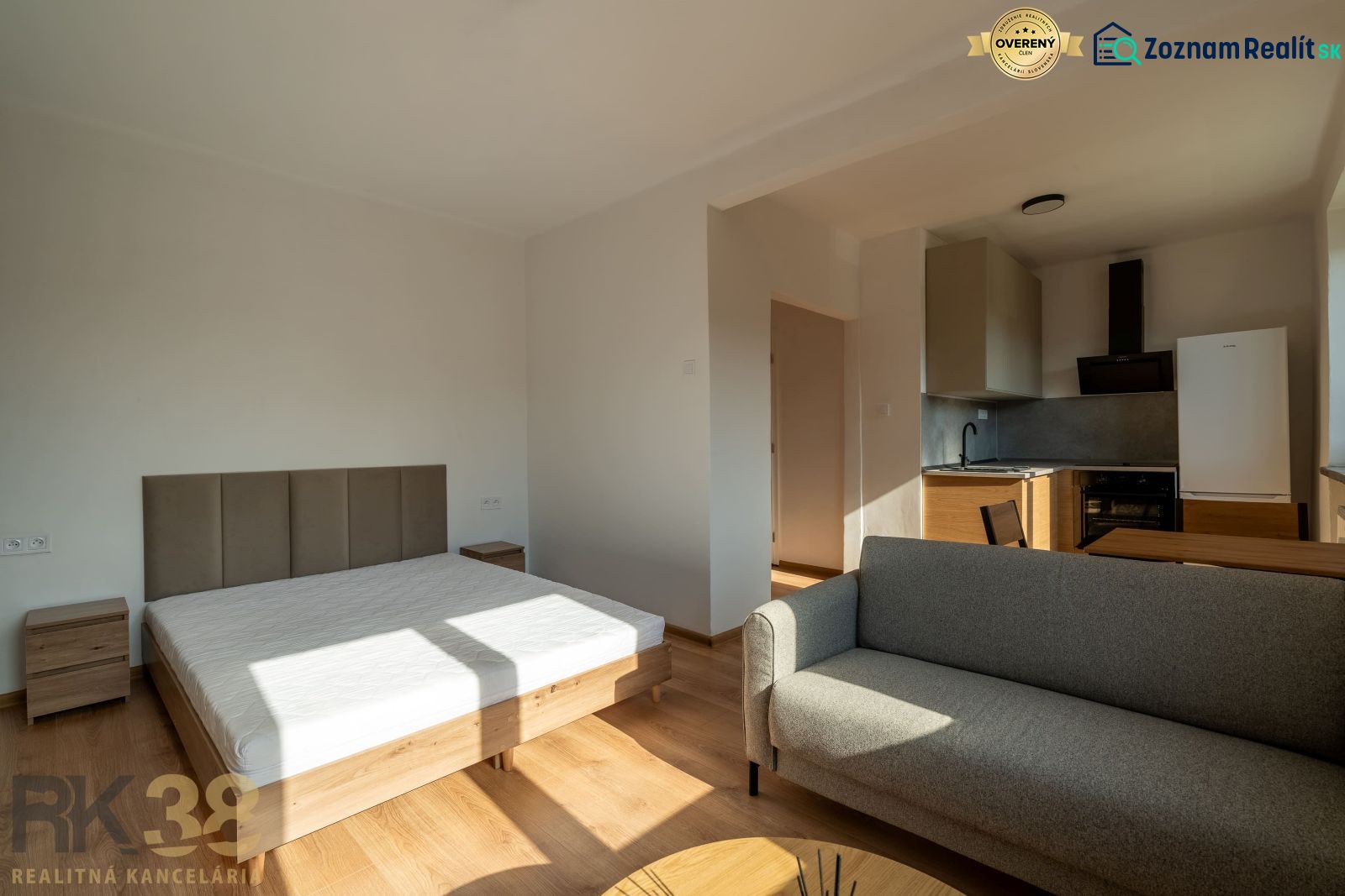 Bed, gray sofa, and kitchen with wooden decor in a studio apartment.