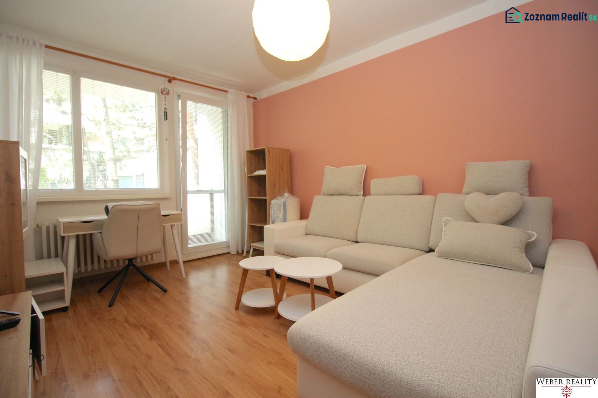Living room in a two-room apartment with a wooden decor floor and a gray sofa.