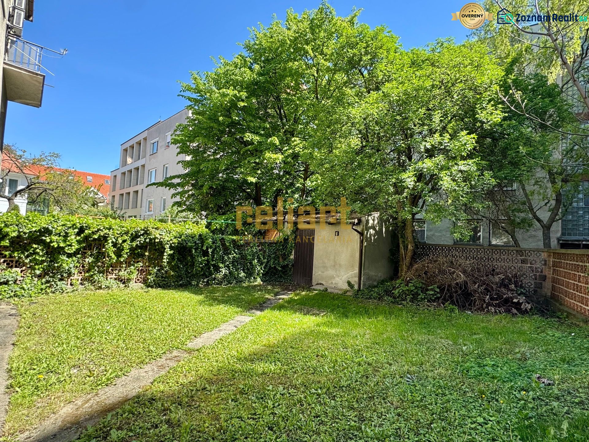 Garden in the Old Town of Bratislava on Krátka Street with a lawn and trees near a family house.