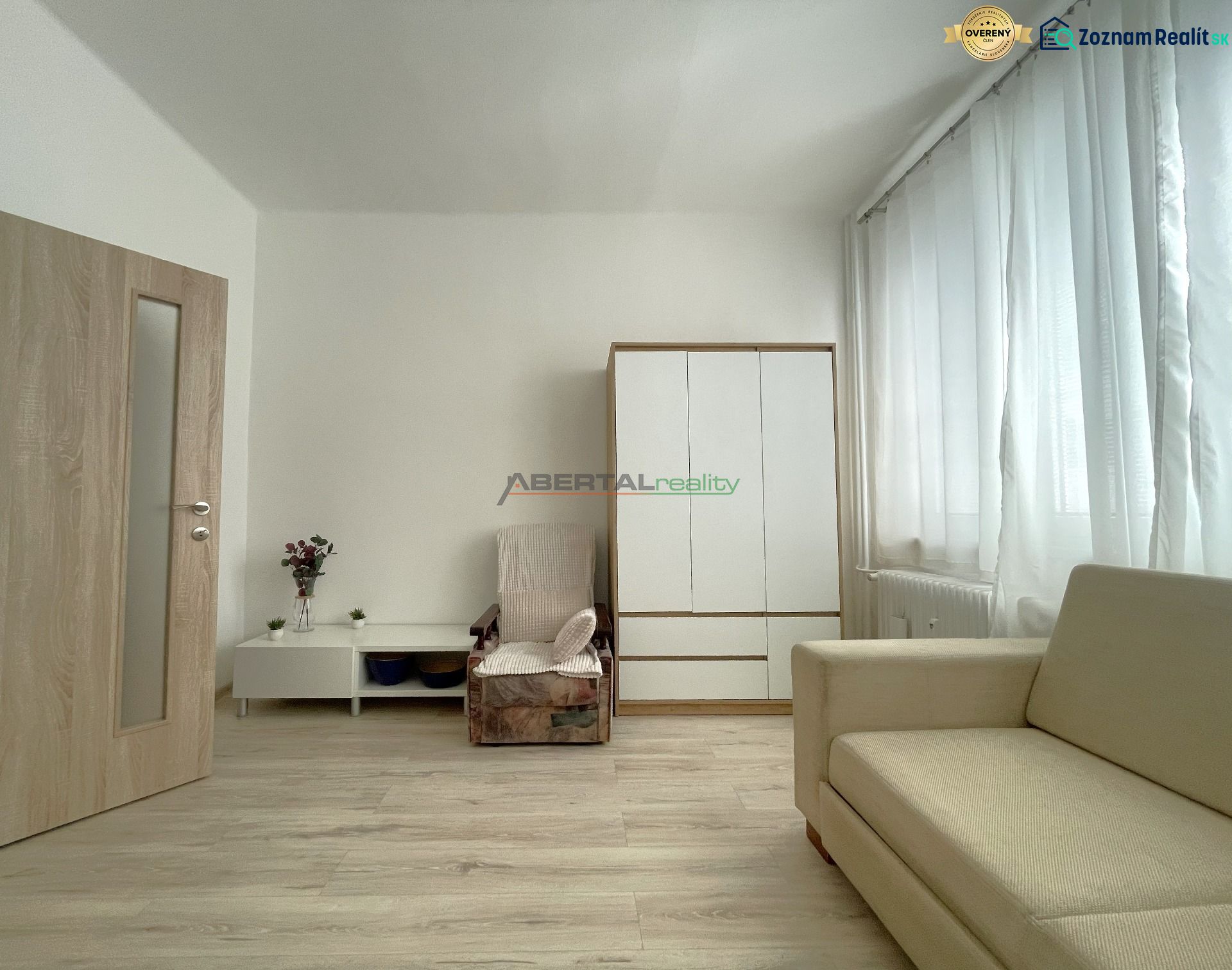 Living room in a 3-room apartment with a wooden decor floor, a sofa, and a wardrobe.