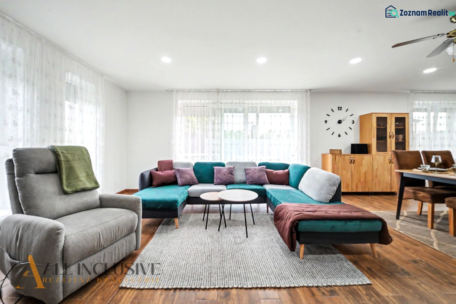 Living room with a sofa, armchair, and wood-patterned flooring in a family house.