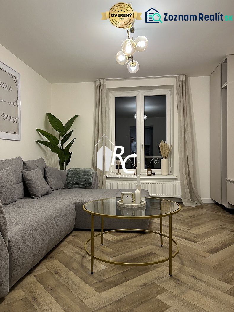 Living room with a sofa, glass table, and wooden decor flooring in a 2-room apartment.