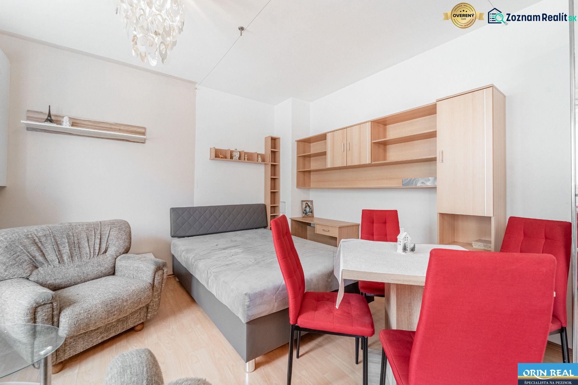 Interior of a 1-room apartment with red chairs and a wooden decor floor.