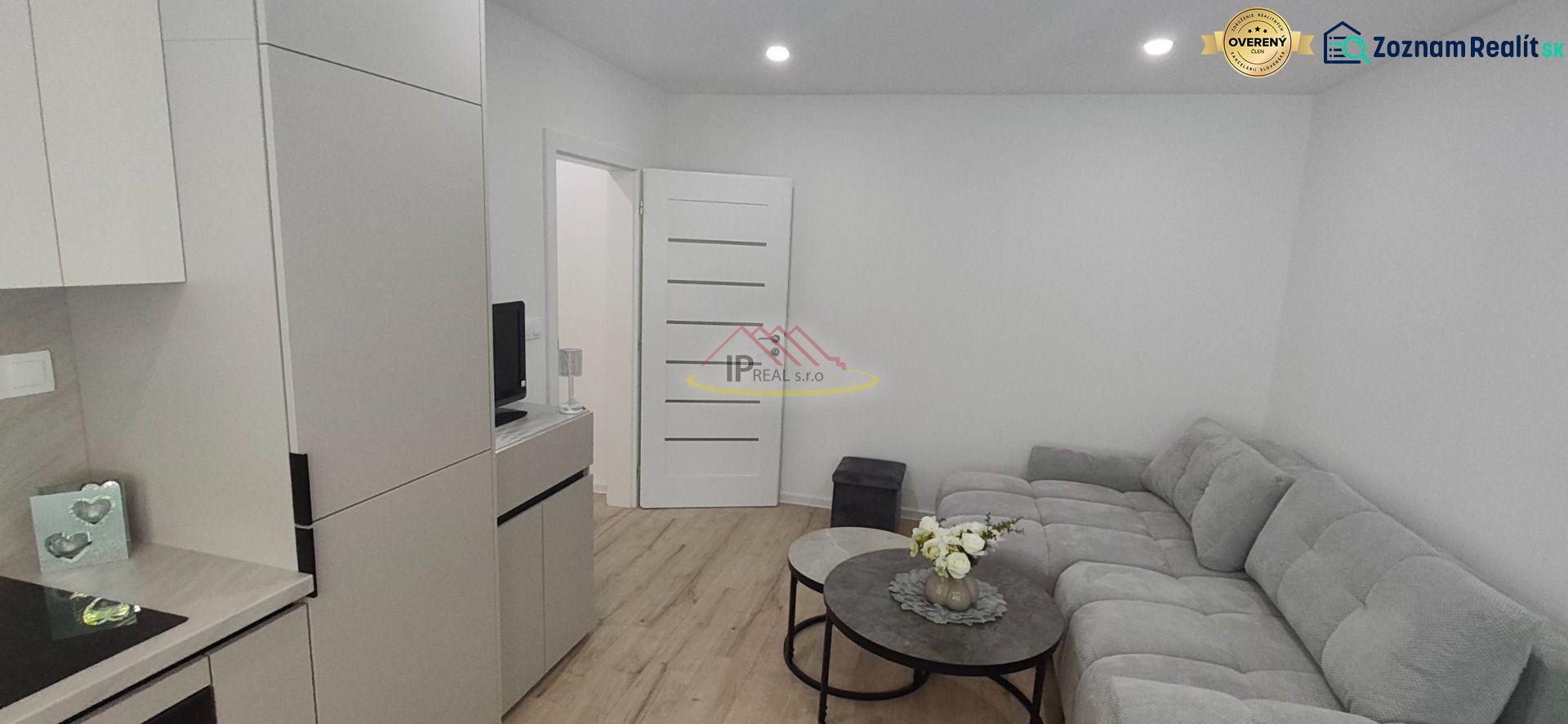 Living room in a three-room apartment with a sofa, tables, and a wooden decor floor.