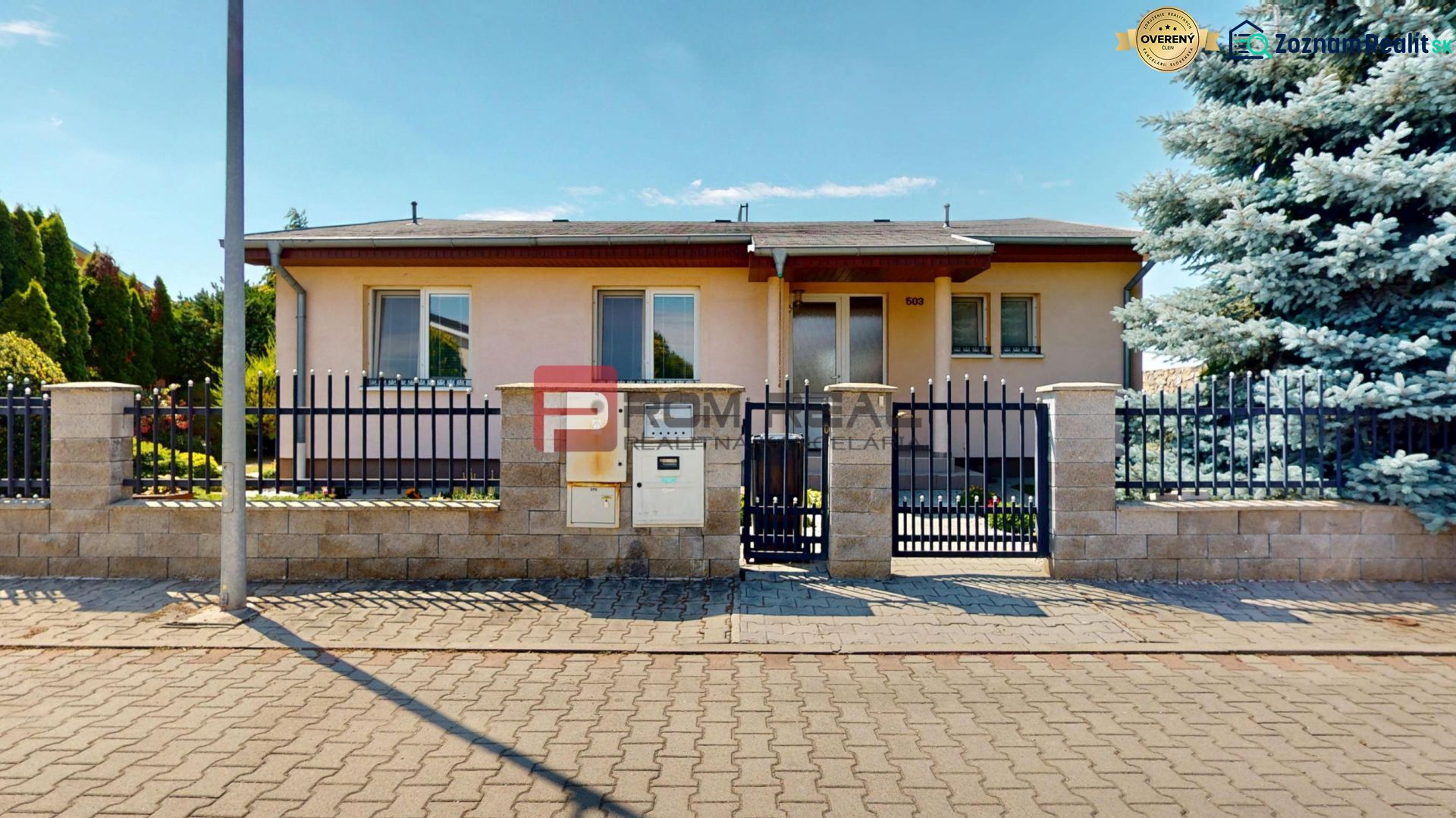 A family house in Senec with a stone and metal fence, surrounded by greenery.