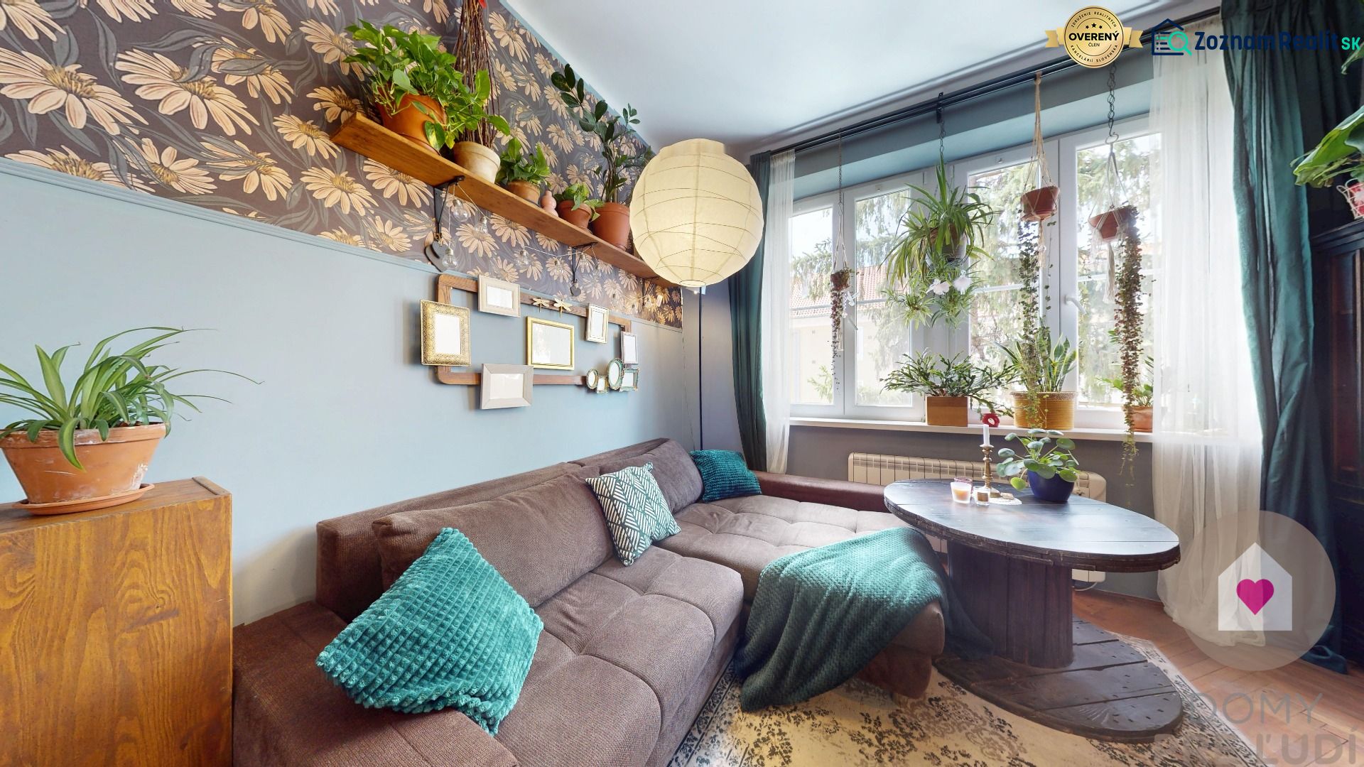 Living room in a two-room apartment with a sofa, flowers, and a wooden table, floor with a wooden decor.
